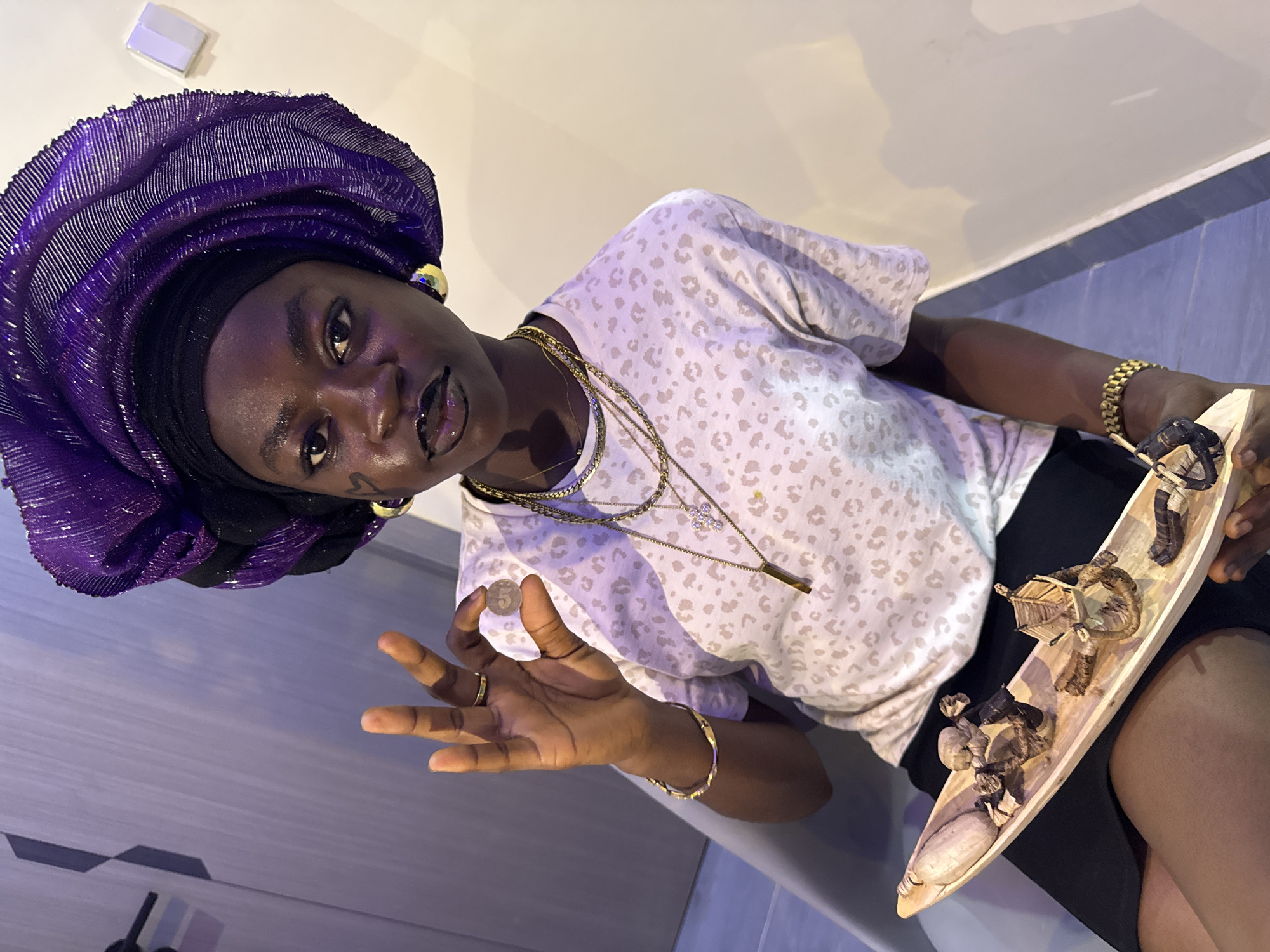 Person in traditional dress poses with miniature objects in Nigeria