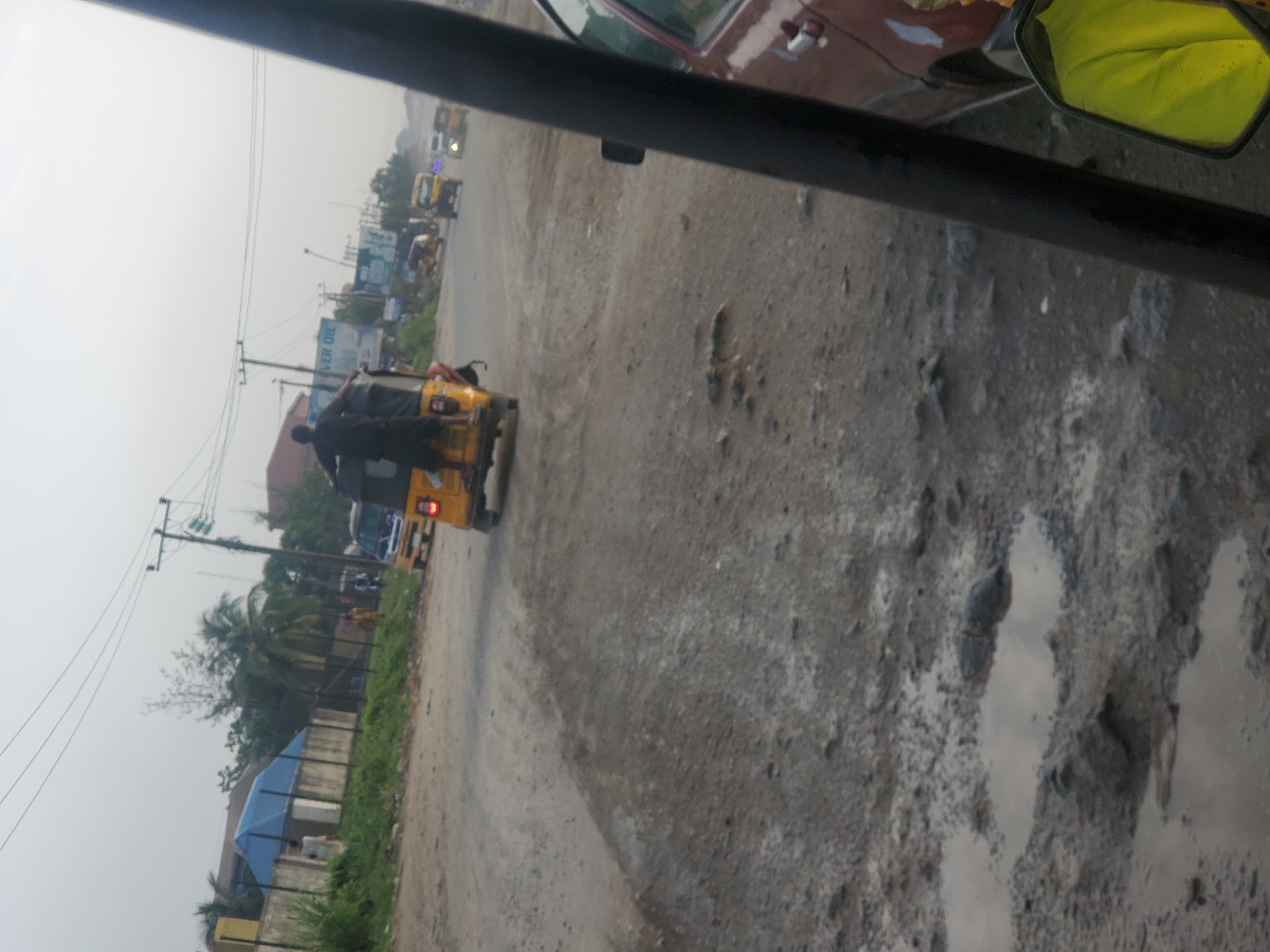 Yellow tricycle navigates pothole-filled unpaved road