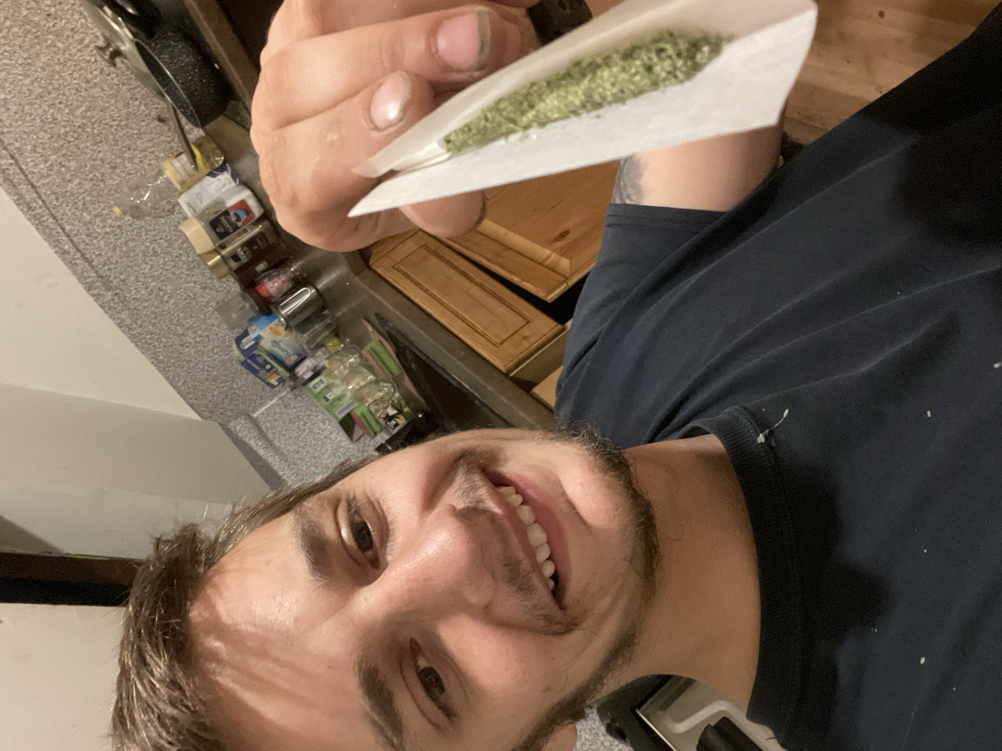 Man photographed with hand-rolled cigarette in kitchen setting