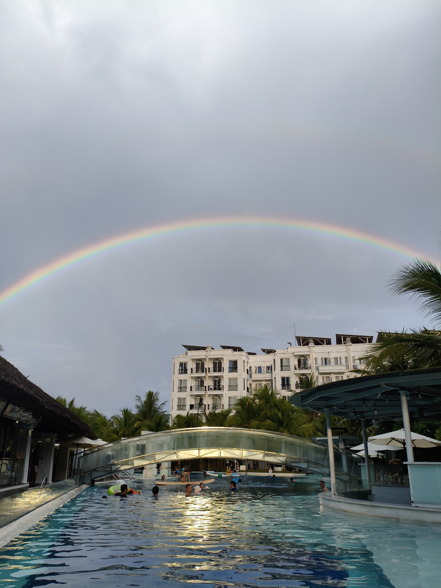 Rainbow over a Nha Trang resort pool on a cloudy morning