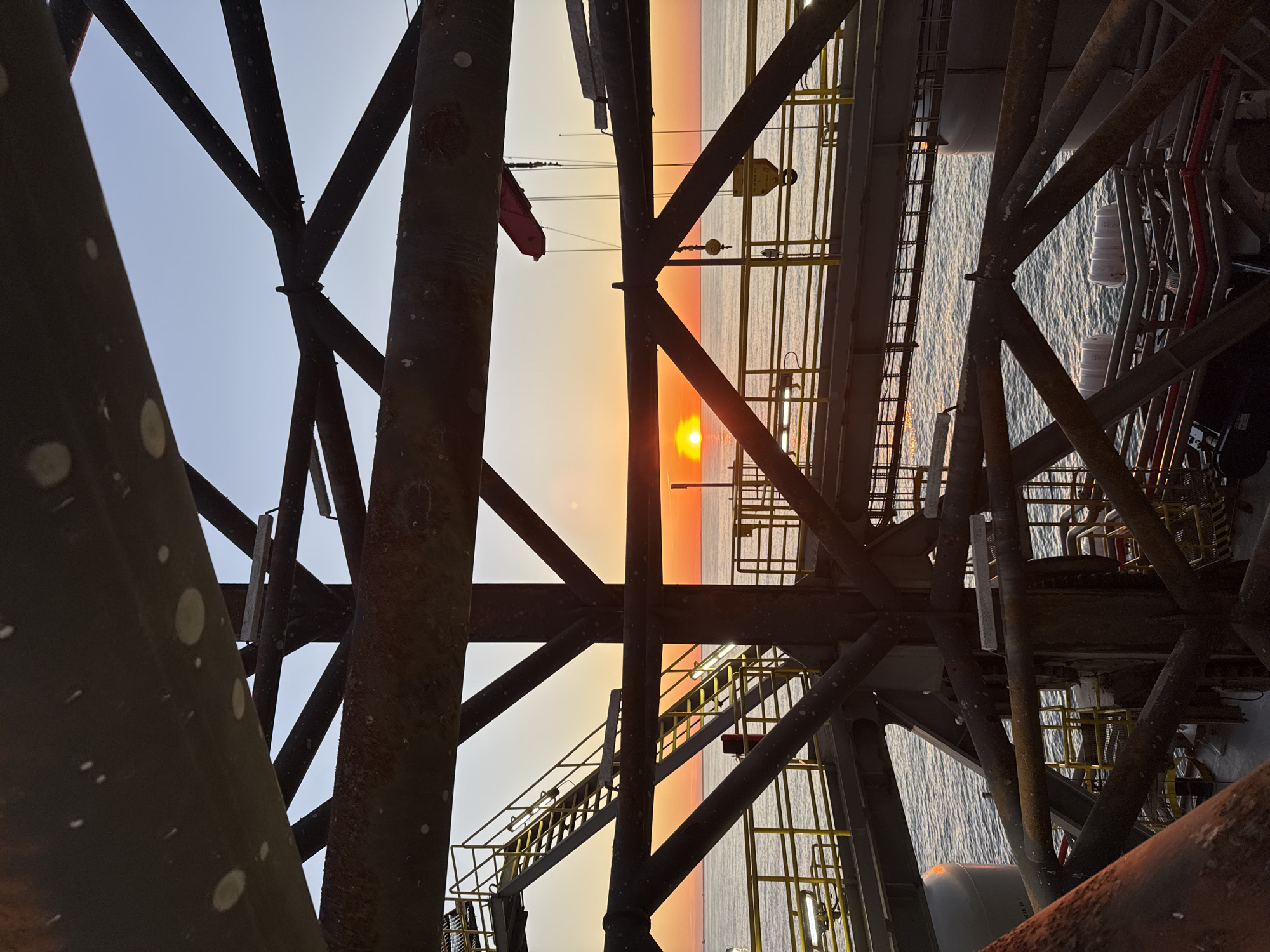 Offshore drilling operations documented during sunset in Italian waters