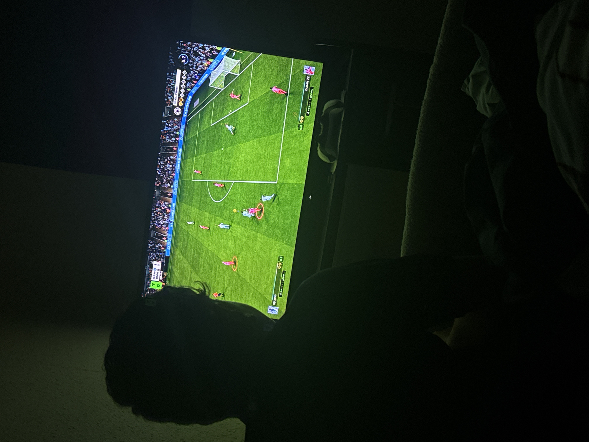 Person plays soccer video game in Welshpool evening