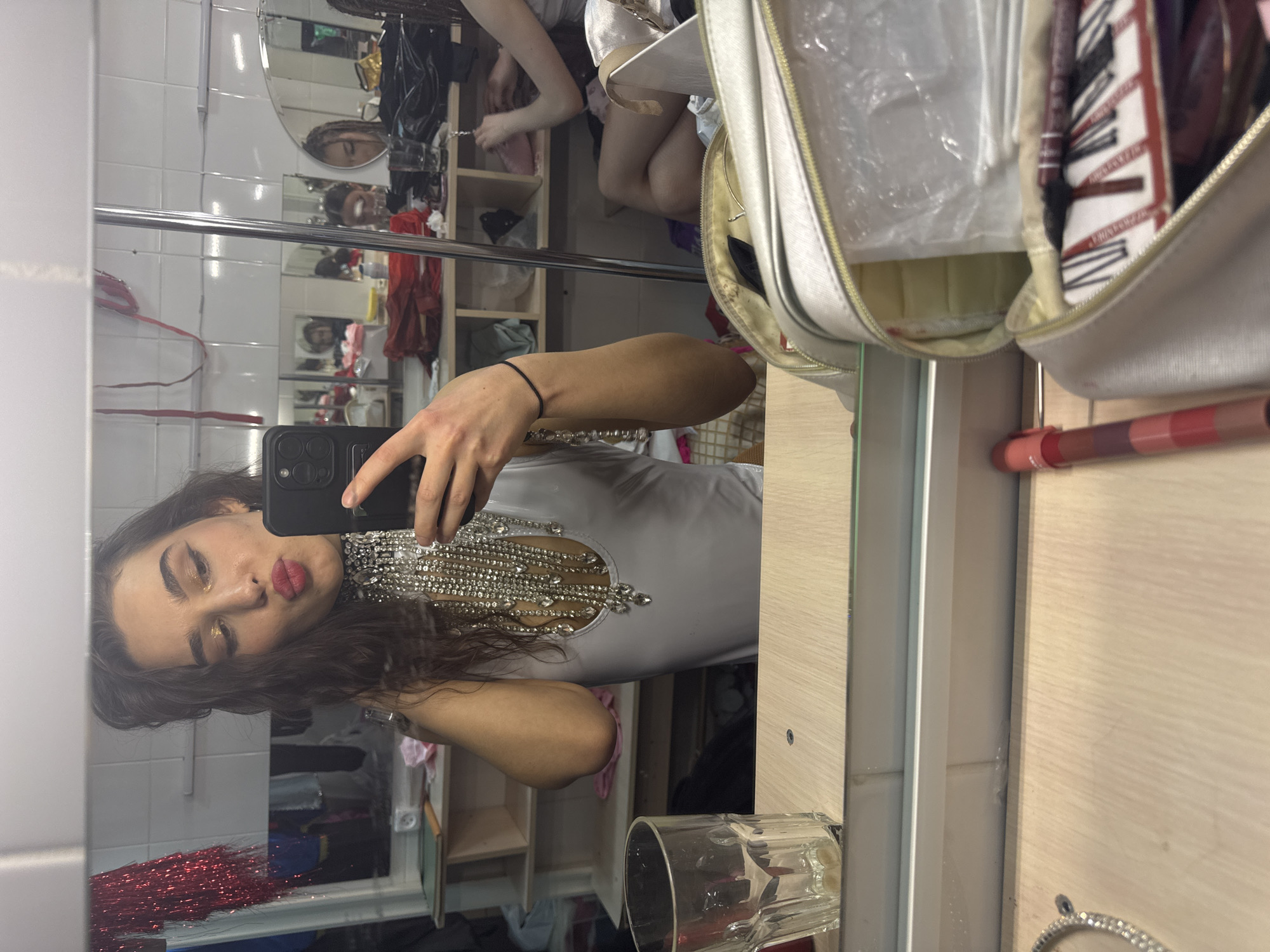 Person takes mirror selfie in white jeweled top