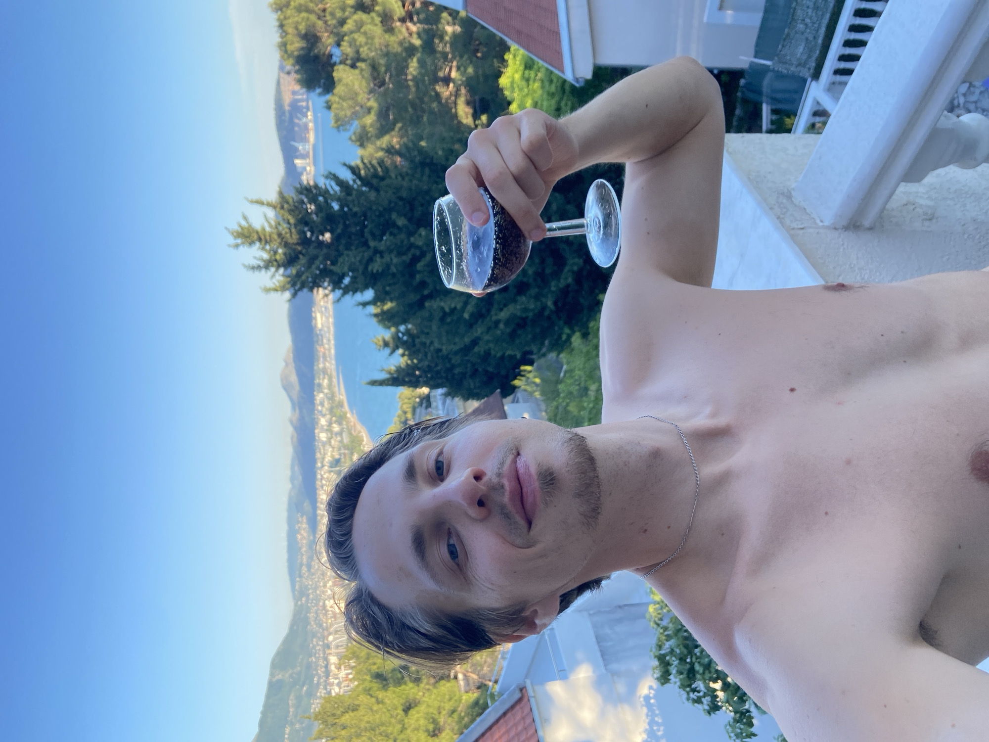 Man pours dark soda into wine glass on Montenegro balcony
