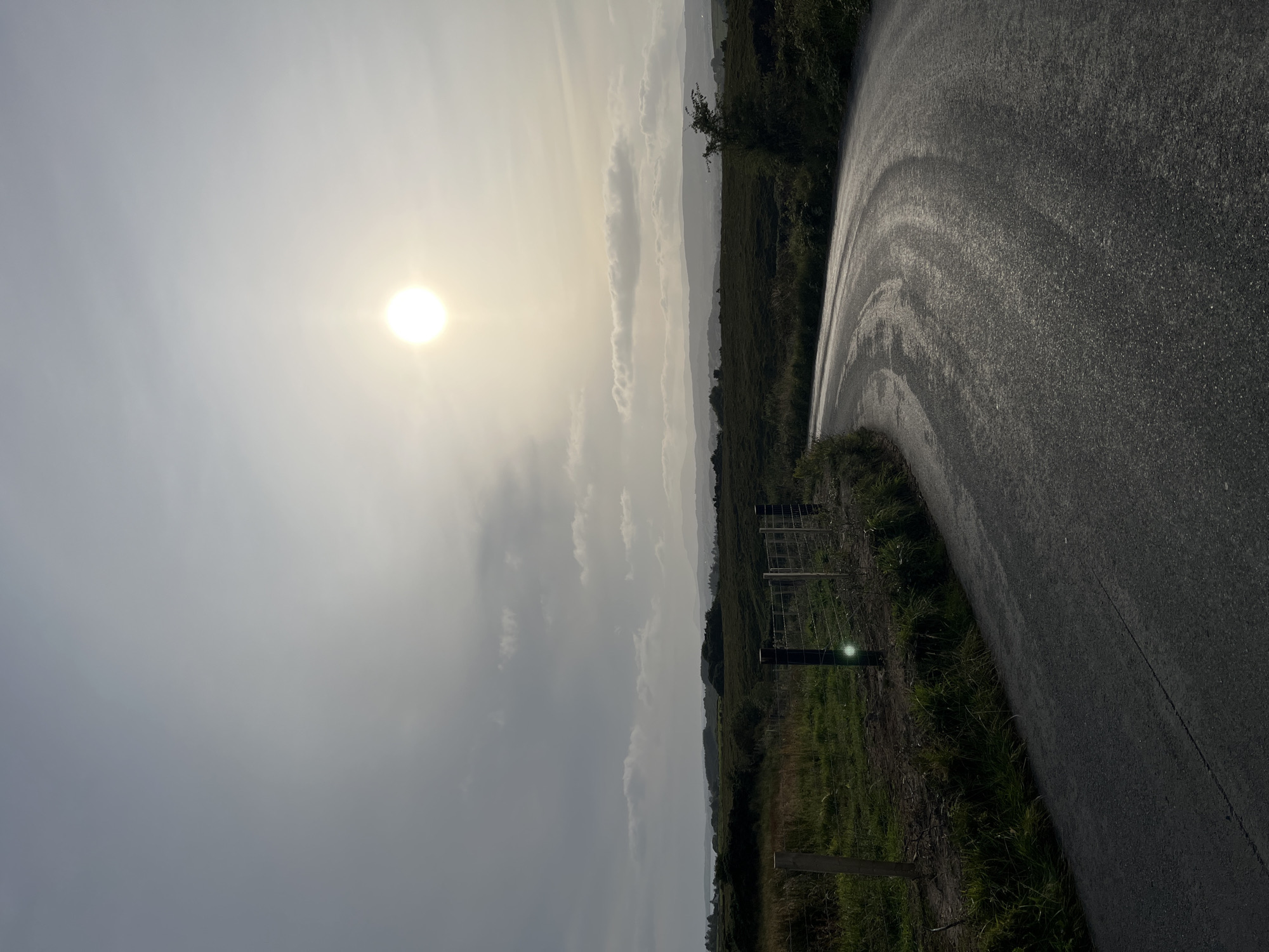 Wet roads and hay bales across a quiet Irish rural landscape