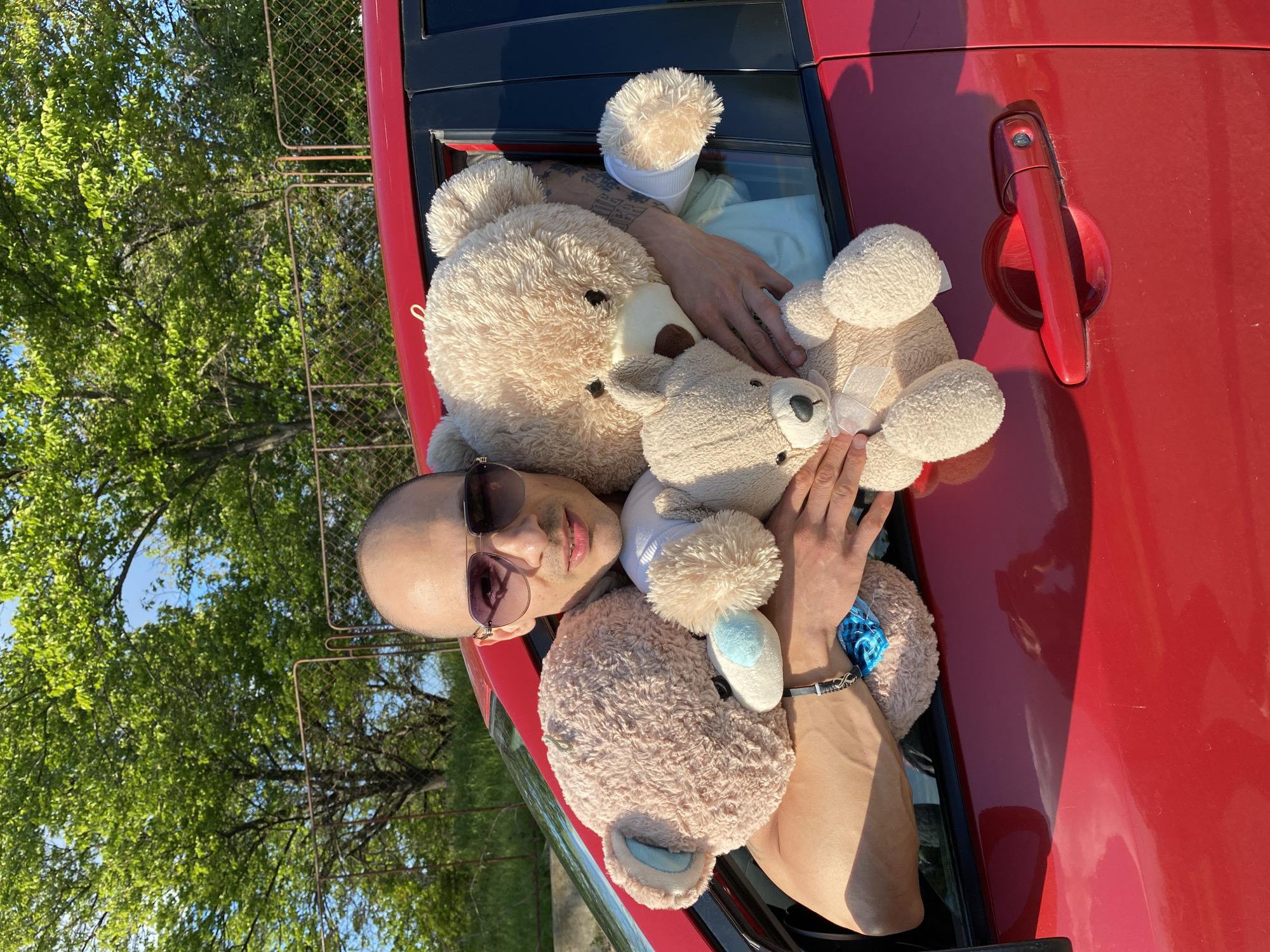 Person poses with teddy bears and red car in Bulgaria