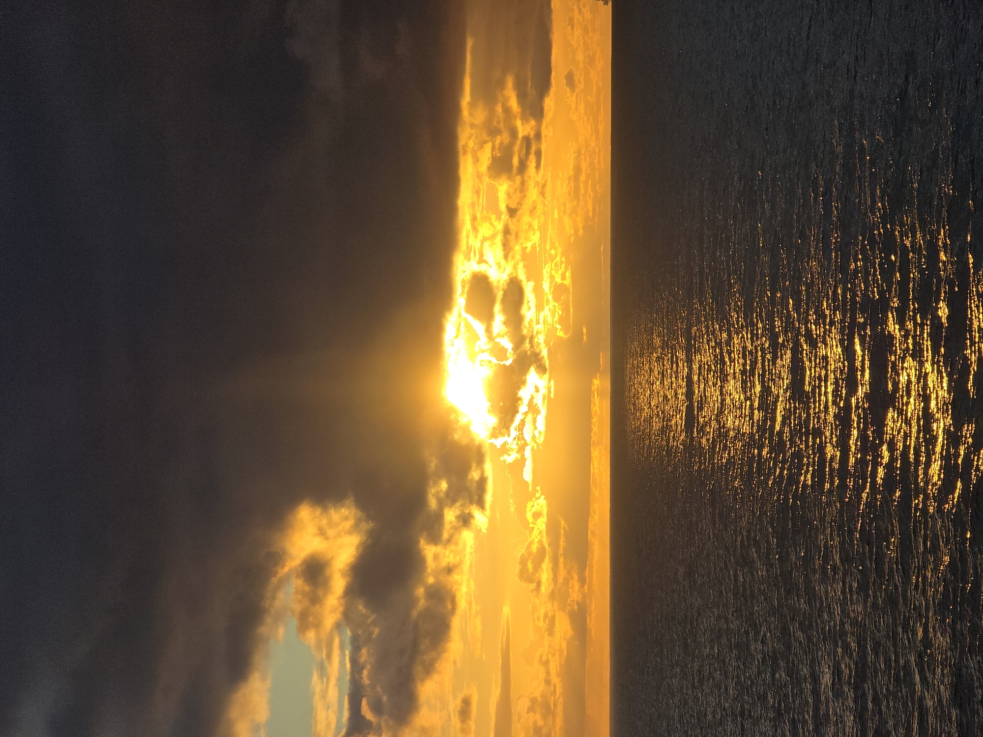 Sunset observed over water with golden light reflection