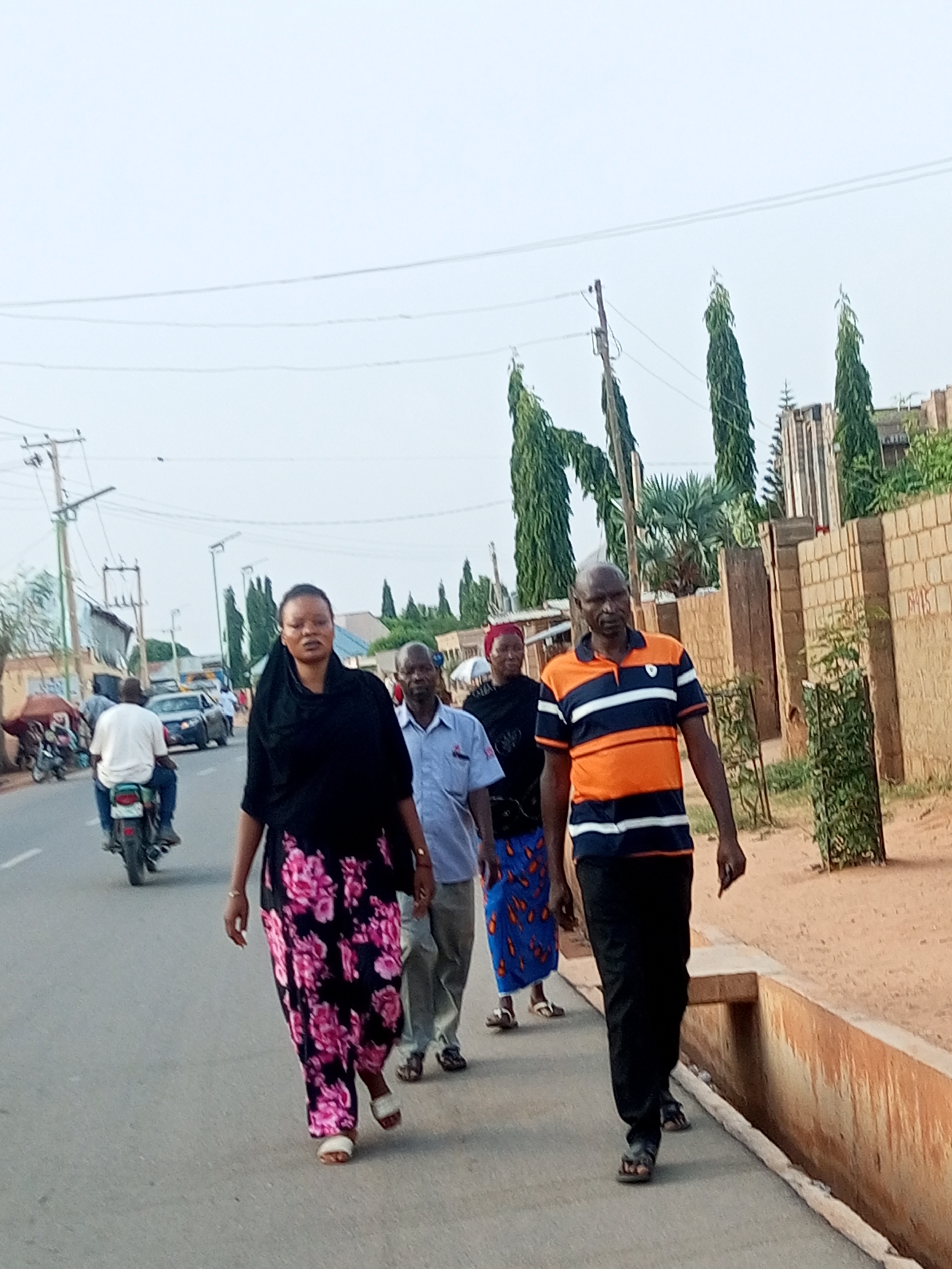 Five pedestrians walk along roadway in Tempure, Nigeria