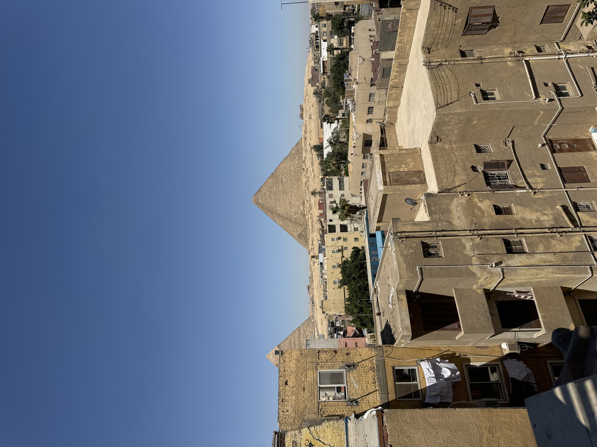 Rooftop view captures Giza pyramids against clear morning sky