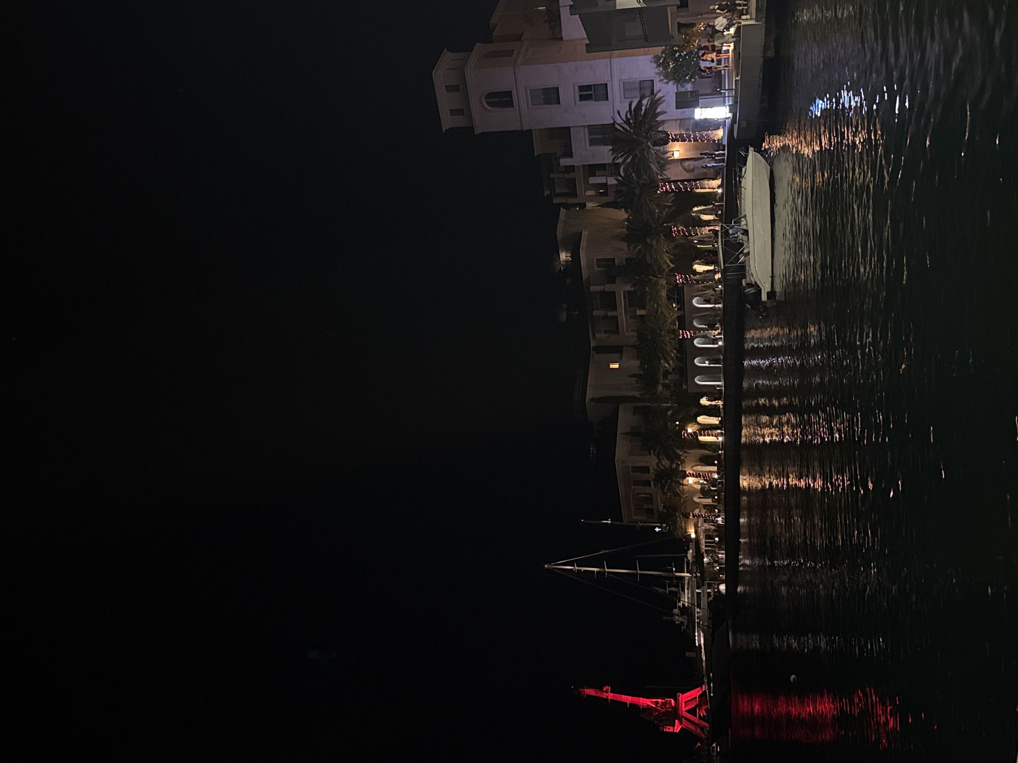 Moonlit harbor town at night, boats docked and streets alive