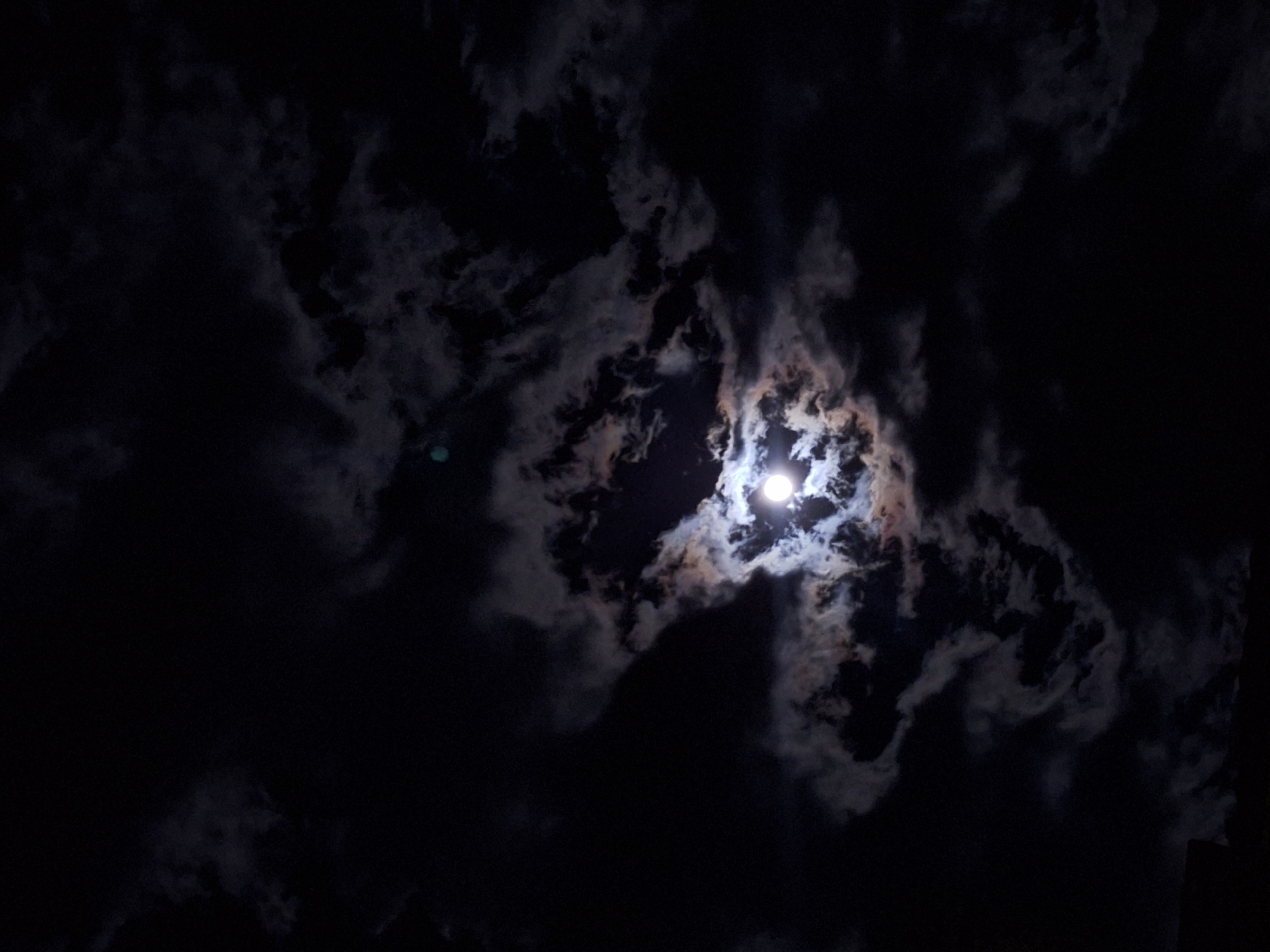 Dramatic moonlit sky observed through clouds over Bulgarian town