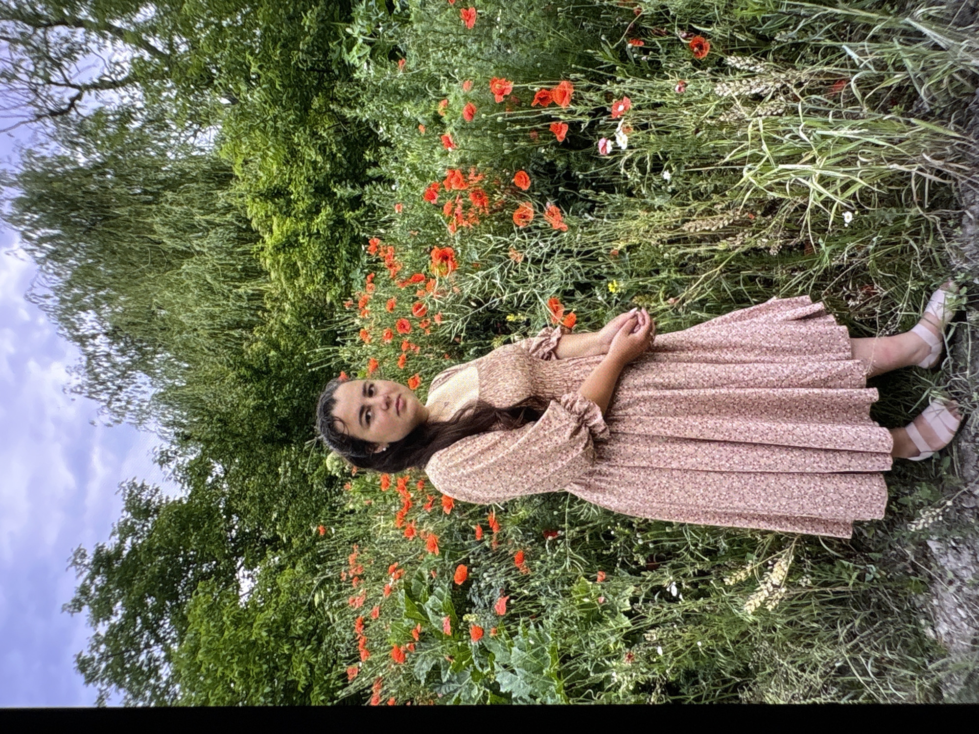 Posing among red poppies in a floral dress