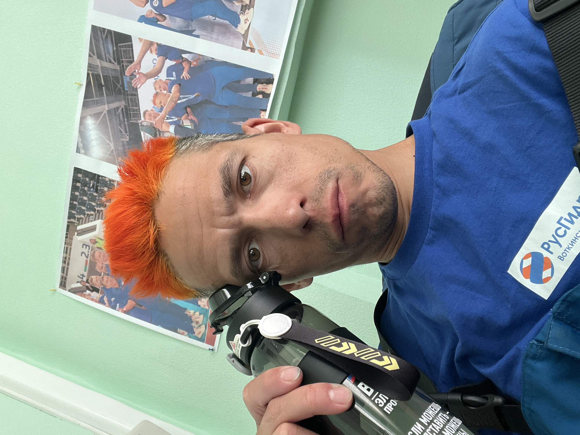 Orange-haired man takes selfie with water bottle in Chaikovsky