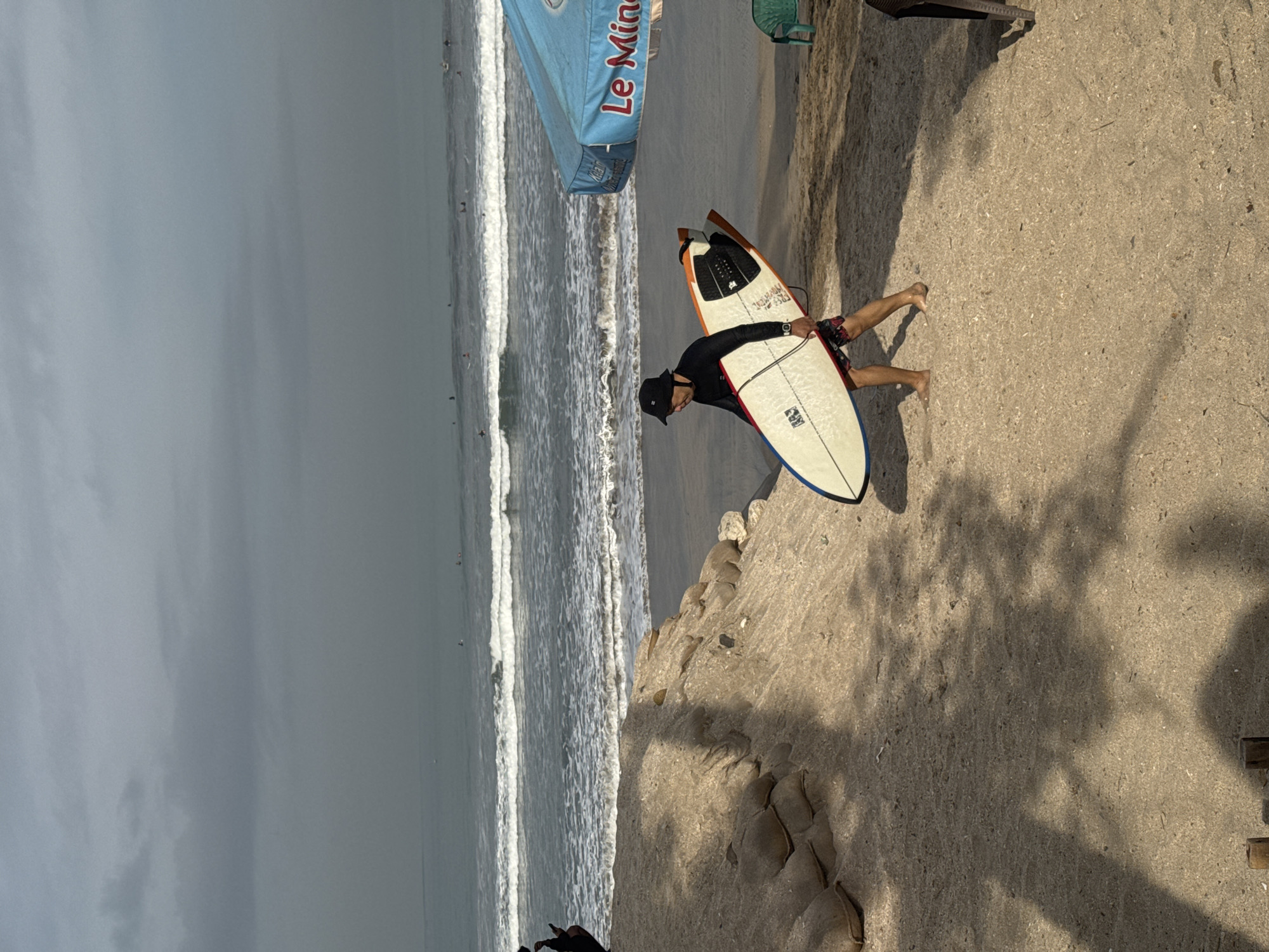 Surfers on Kuta Beach under overcast skies