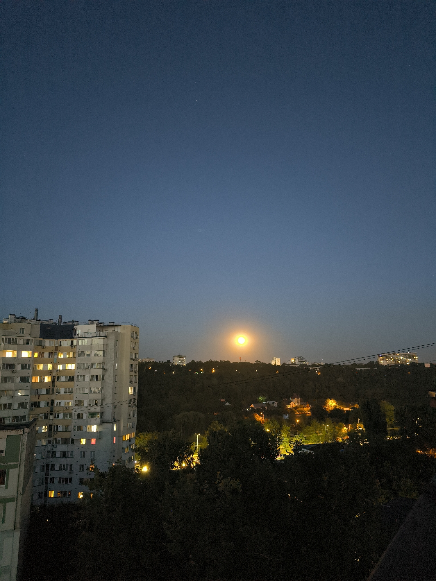 Chișinău residential skyline at twilight, moon rising over Soviet blocks