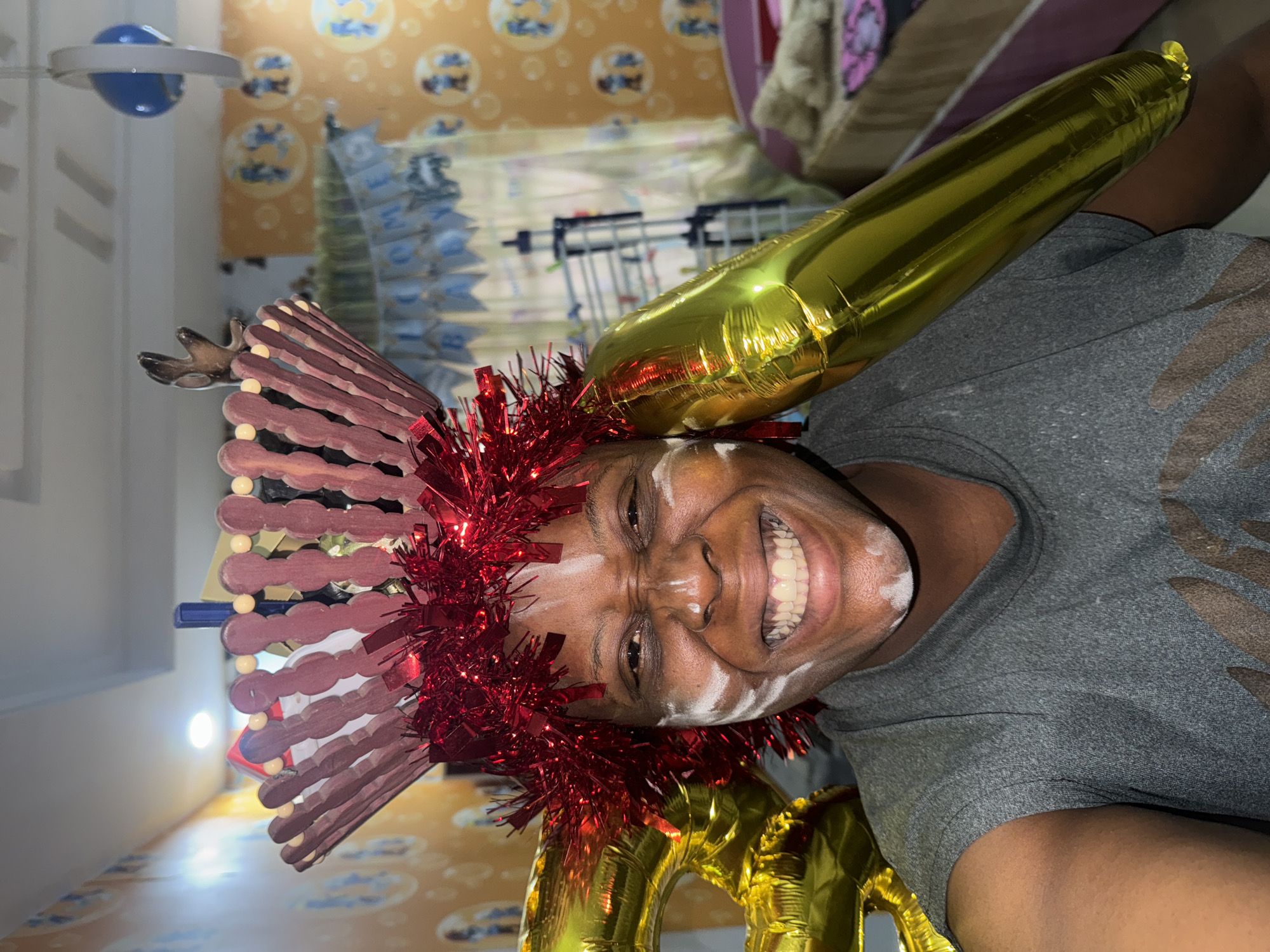 Person celebrates in festive costume with face paint and balloons