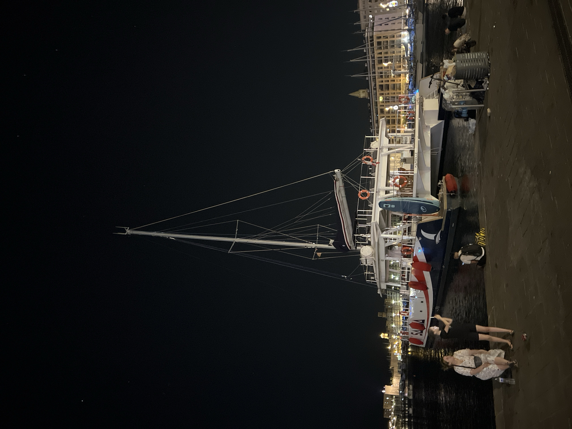 White catamaran docked at a Marseille marina after dark