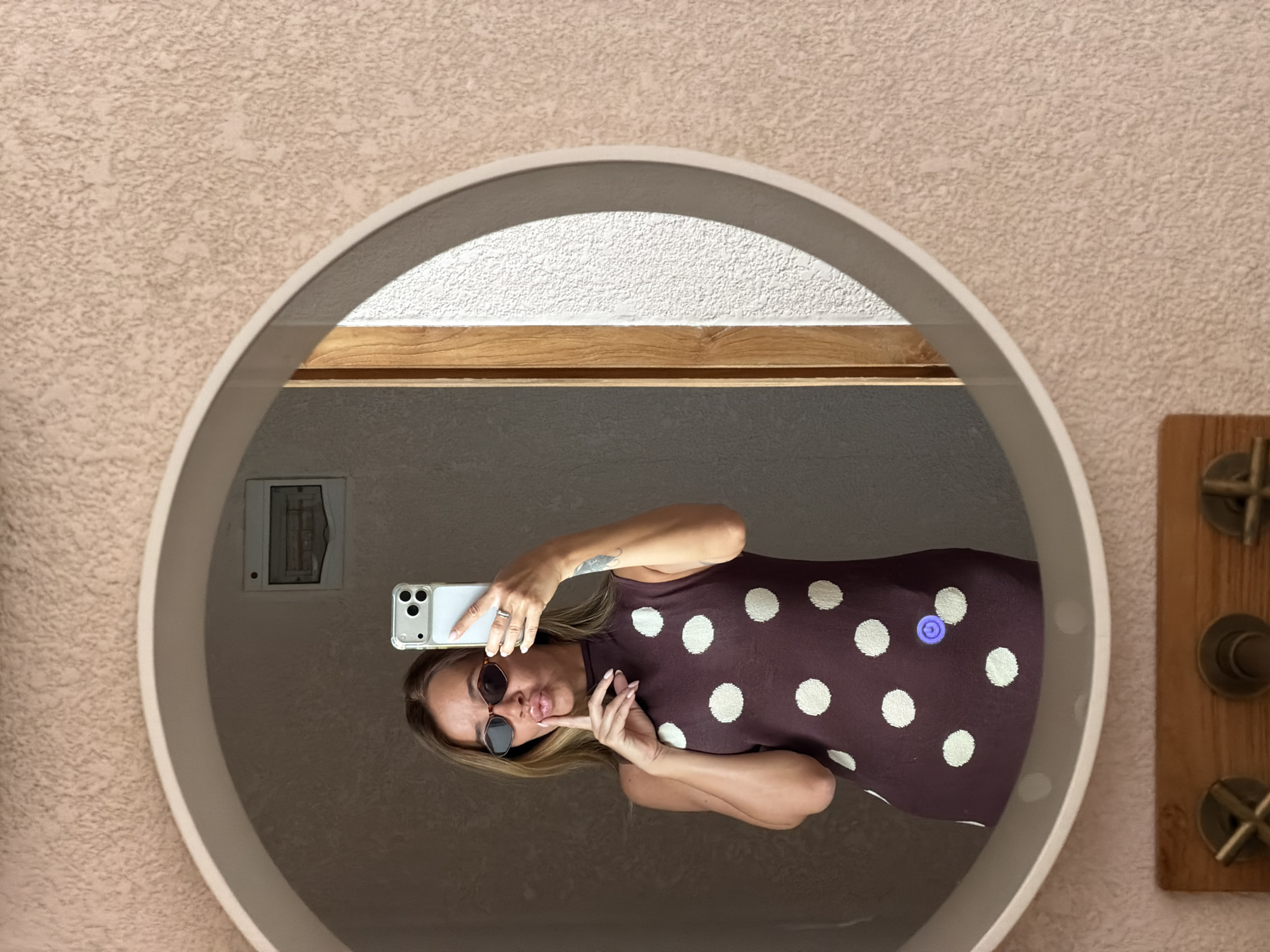 Mirror selfie in a warmly lit Mengwi bathroom, polka-dot dress