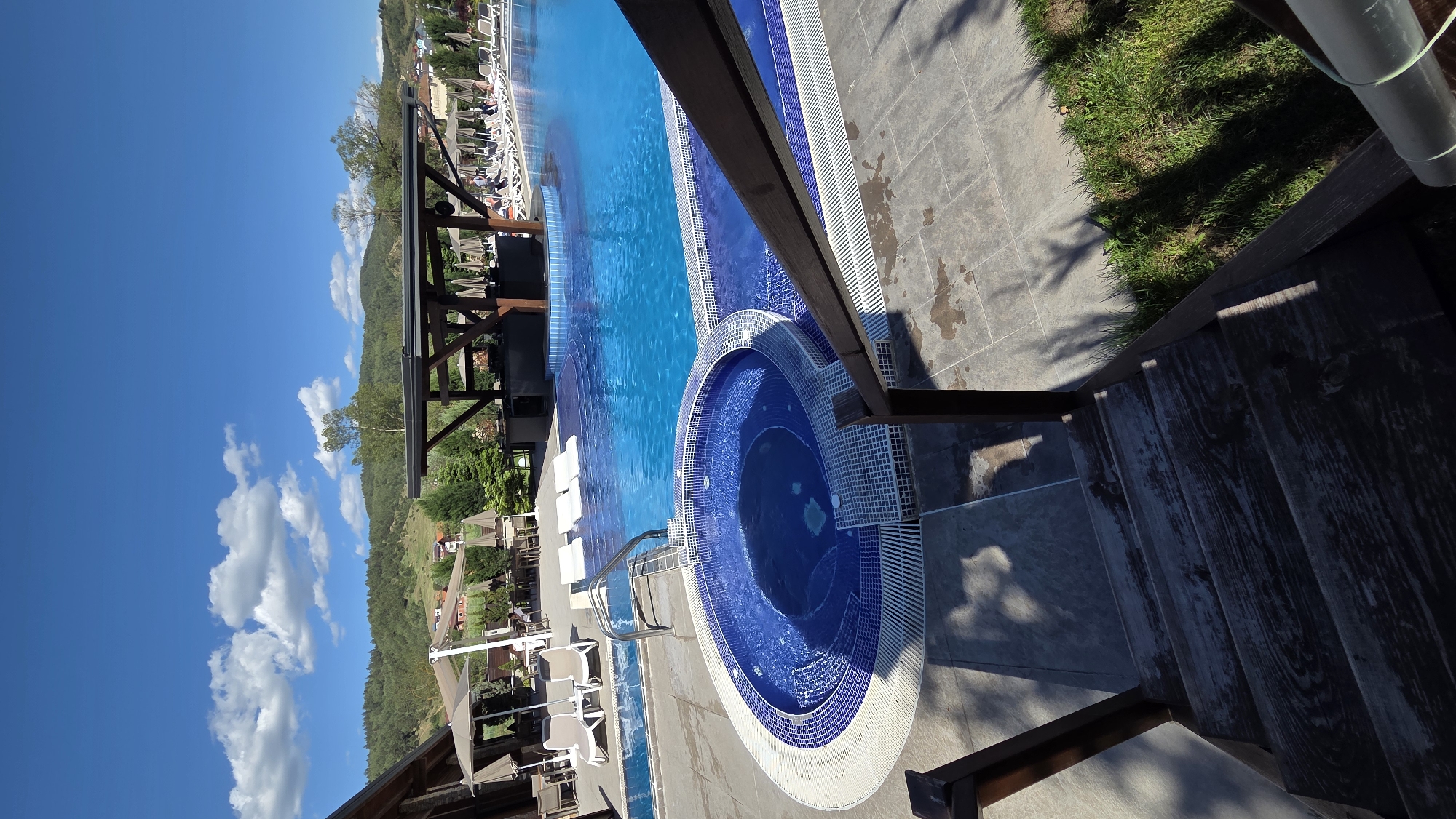 Person enjoys poolside leisure time with mountain backdrop
