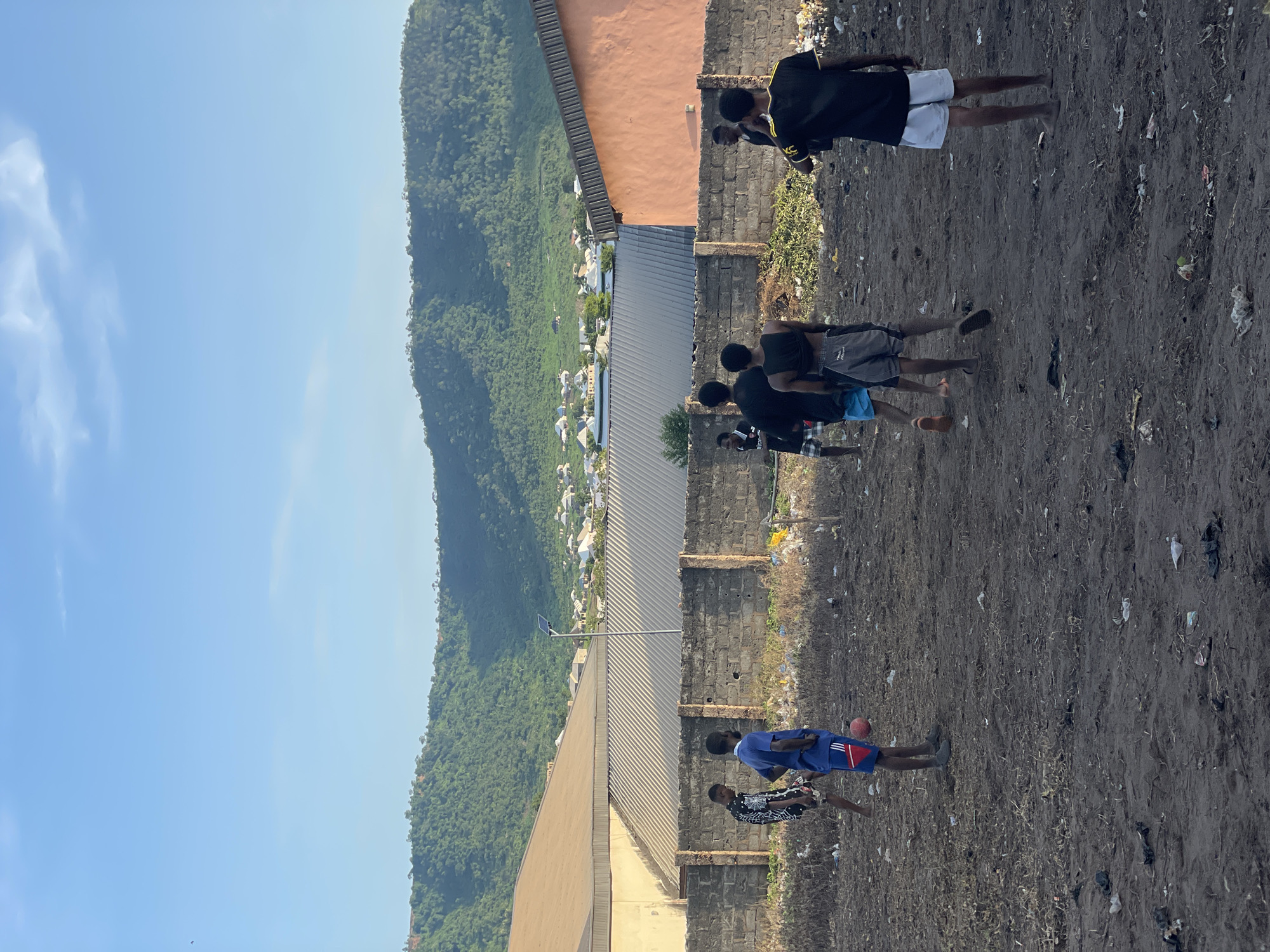 Pickup soccer on a rough dirt lot in a semi-urban neighborhood