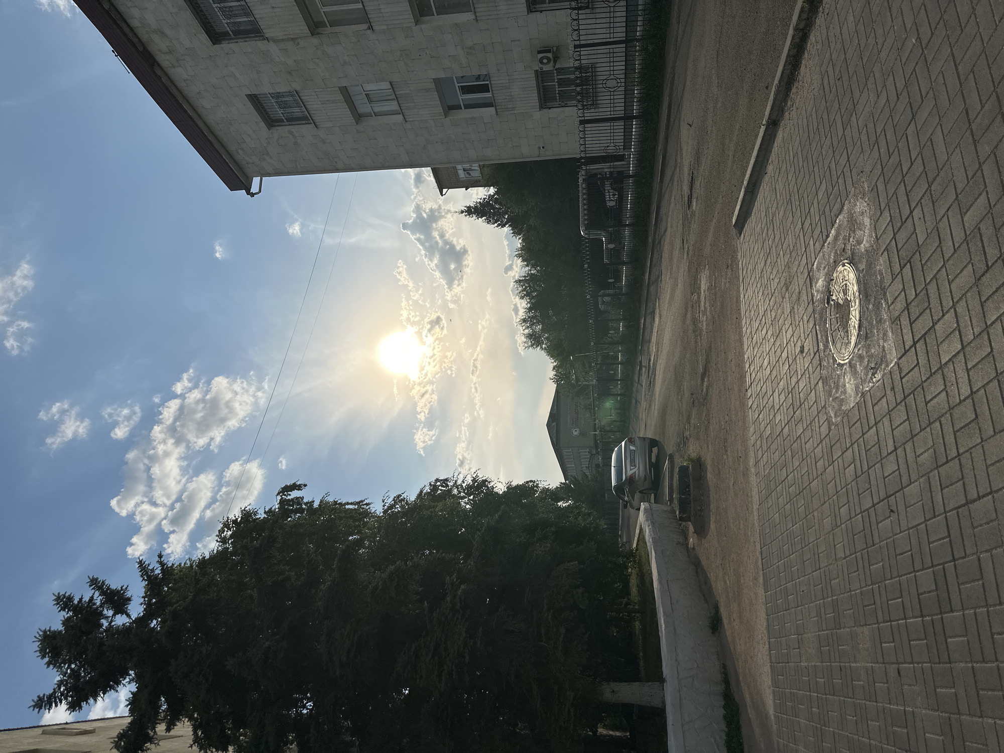 Quiet Kokshetau street at golden hour, sedan parked roadside