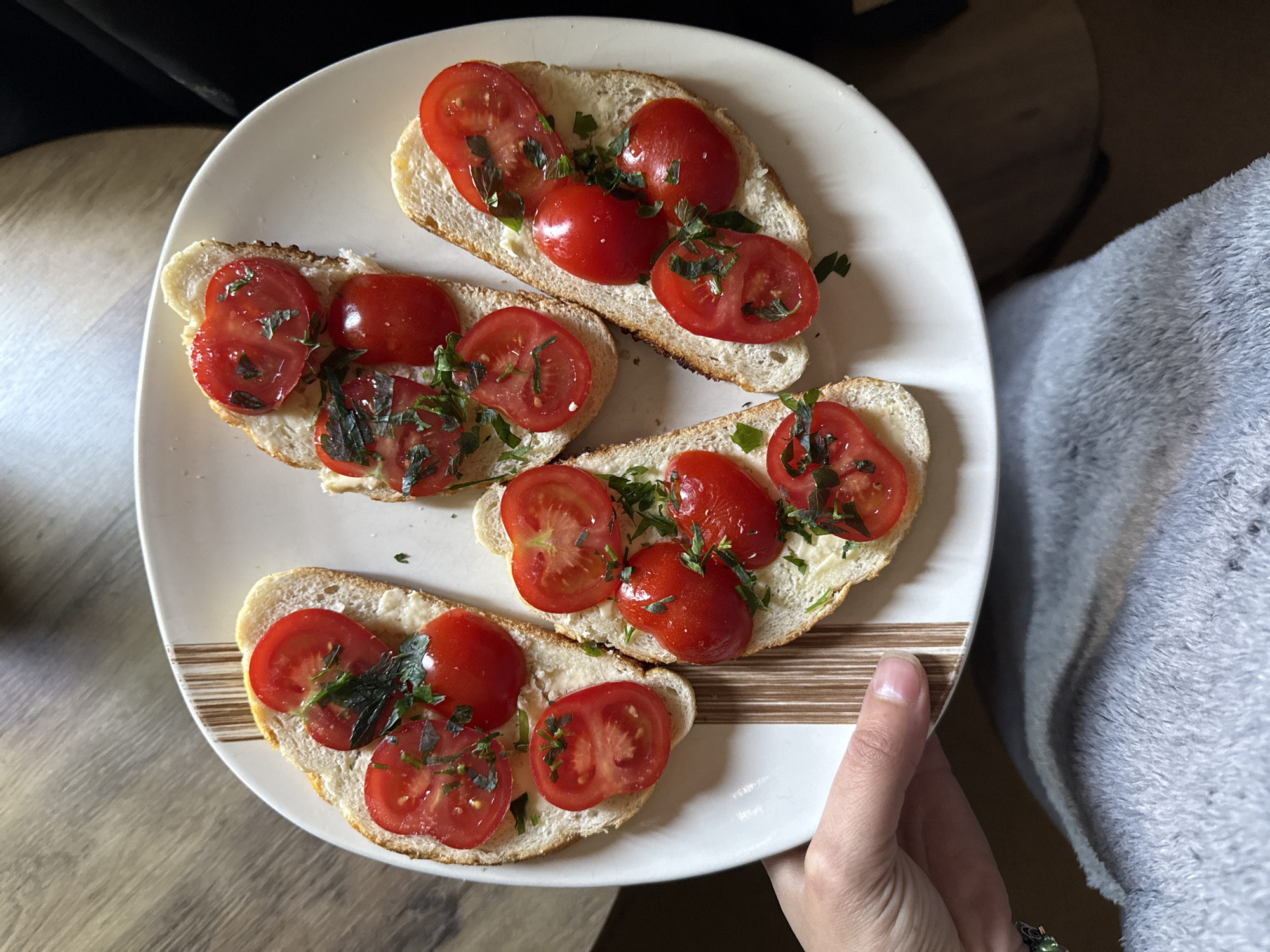 Person holds tomato-herb topped baguette slices in Great Yarmouth