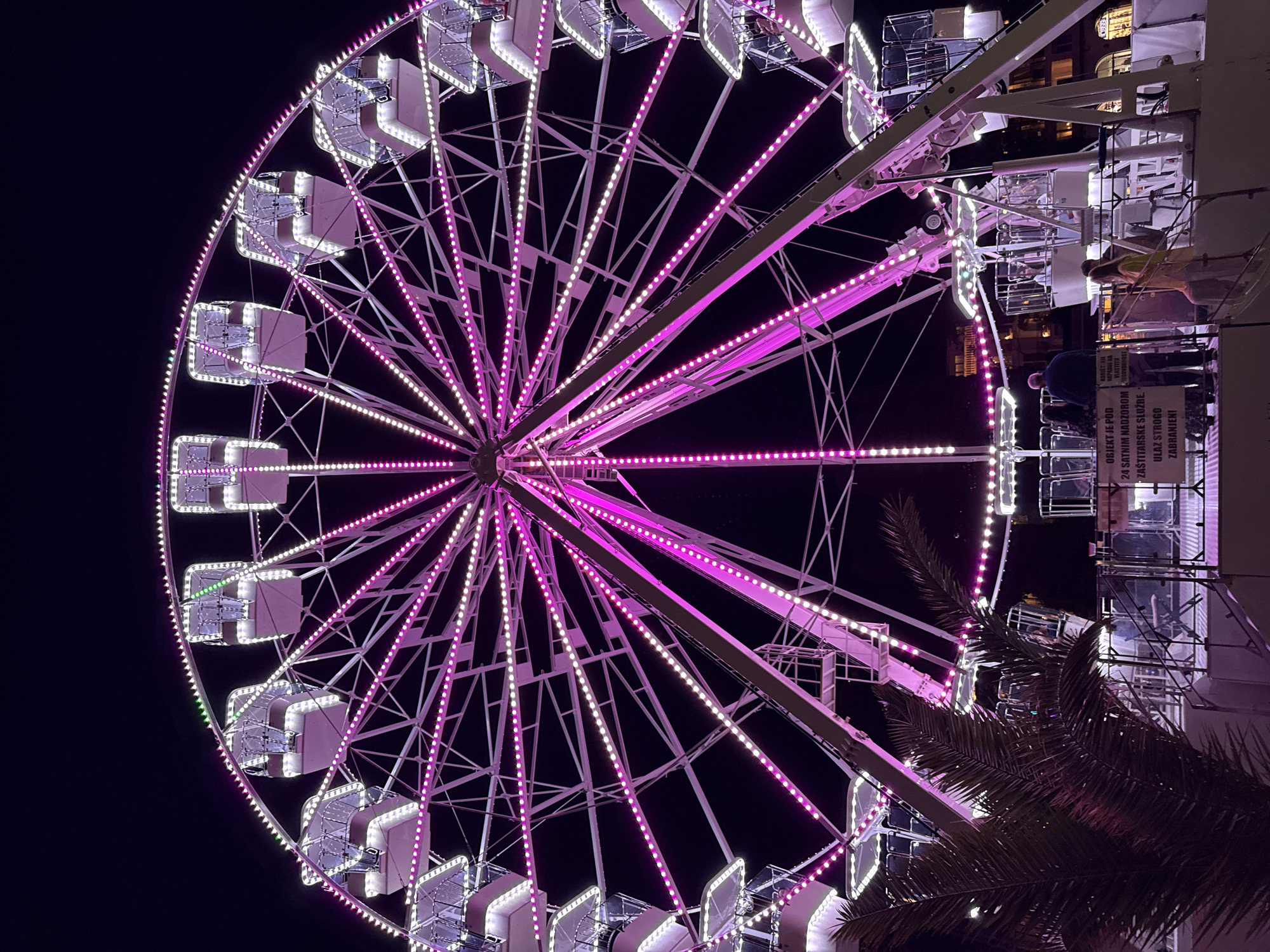 Evening scenes around Budva's illuminated waterfront Ferris wheel