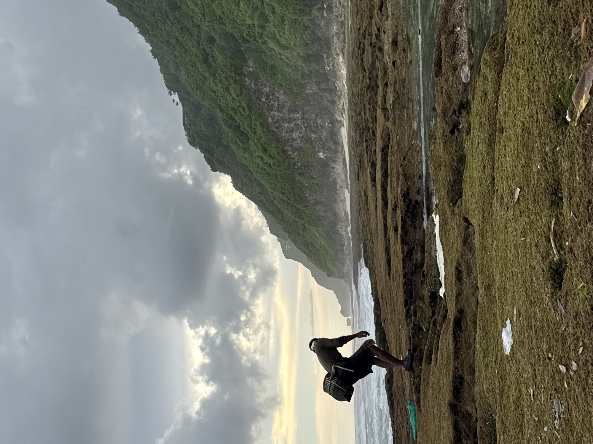 Person observed on rocky shore near clifftop structures in Pecatu