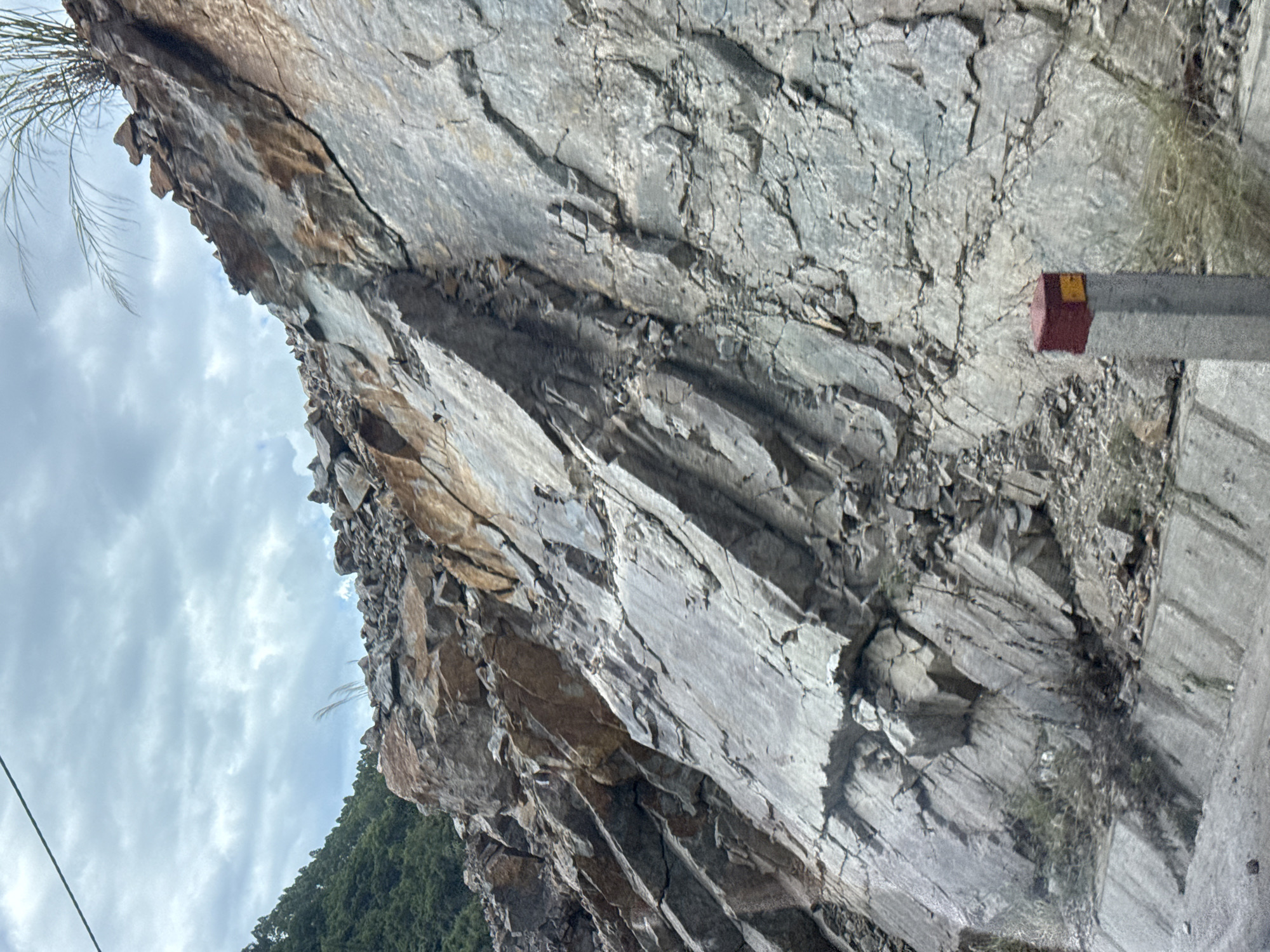 Fractured rock face with mineral staining lines a road in Binh Khe