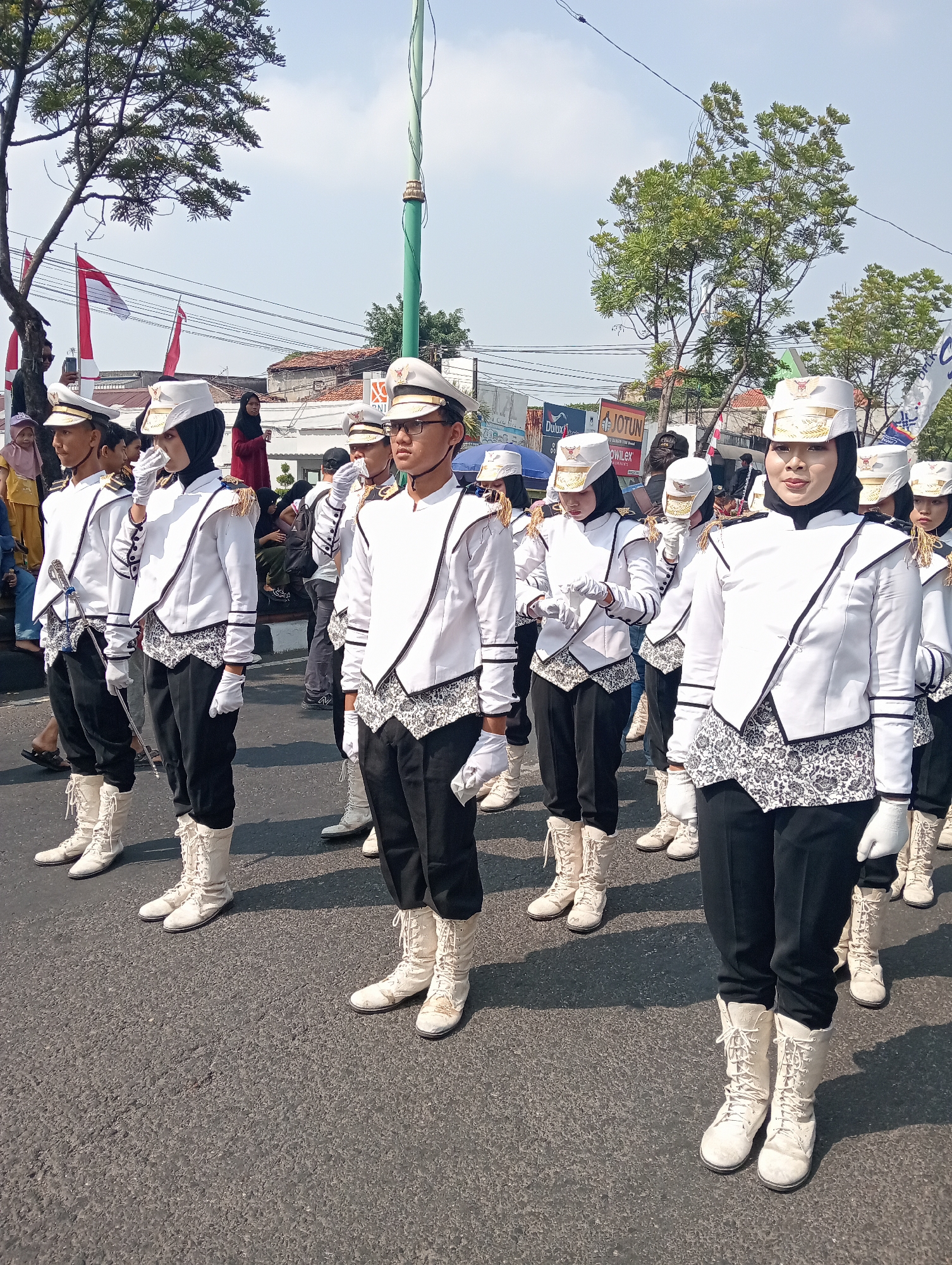 Uniformed marching band parades through Demak streets with flags and banner
