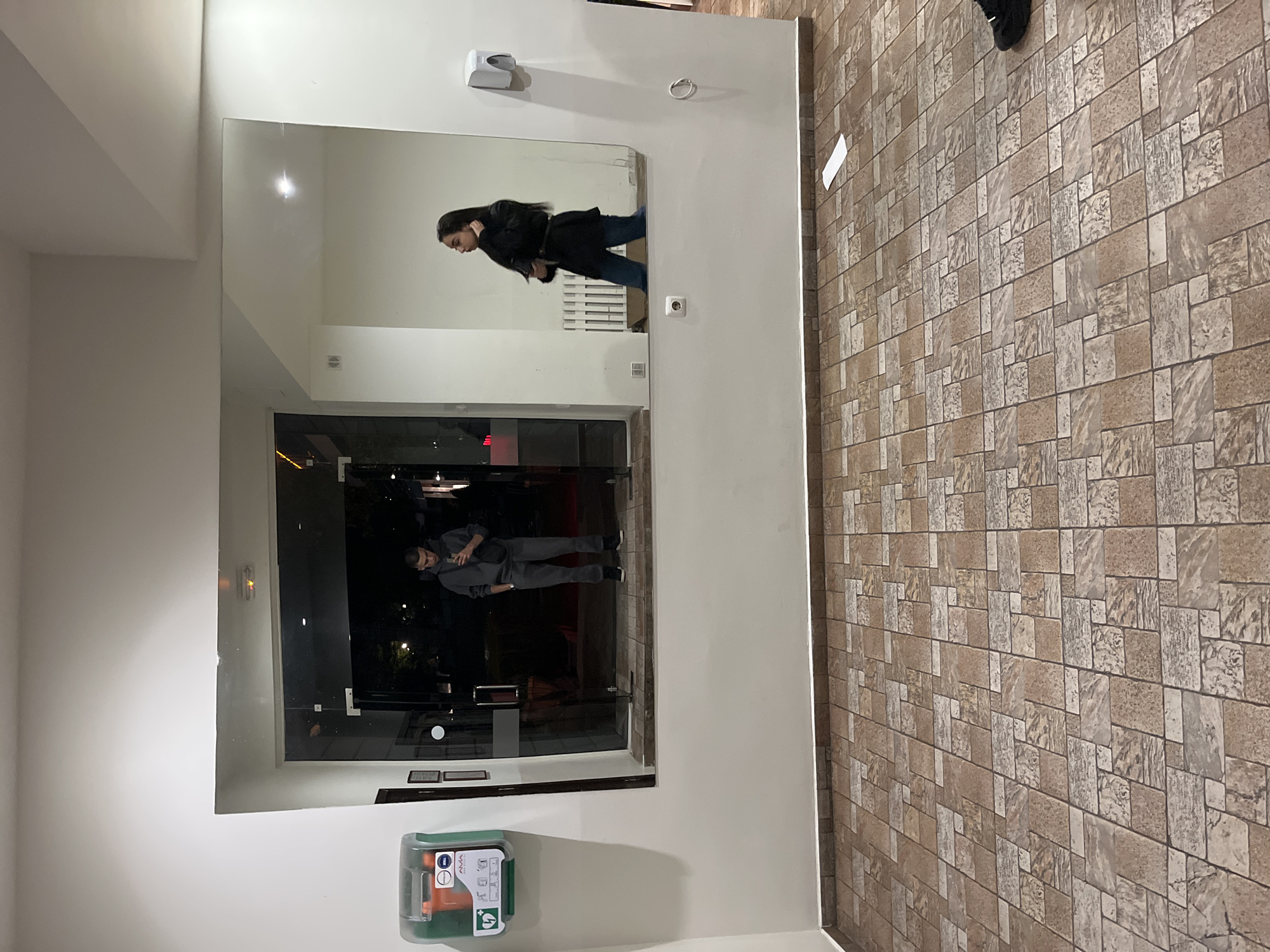Mirror reflection captures two people in Karlovo building lobby