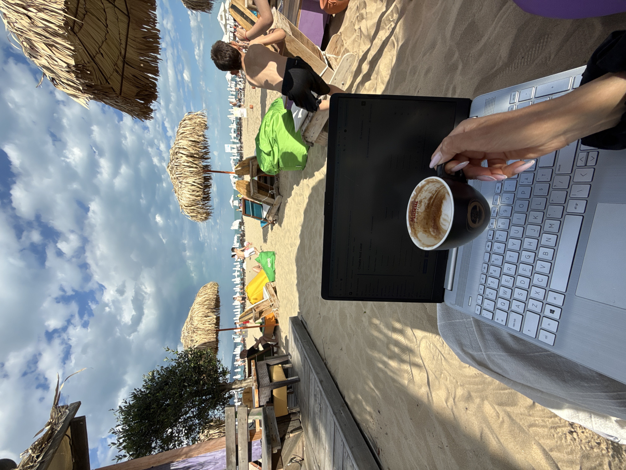 Woman works on laptop with coffee at Bulgarian beach