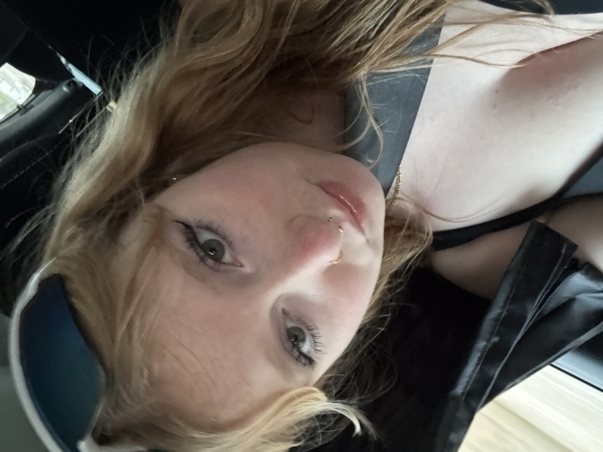 Blonde passenger with nose ring travels through suburban neighborhood