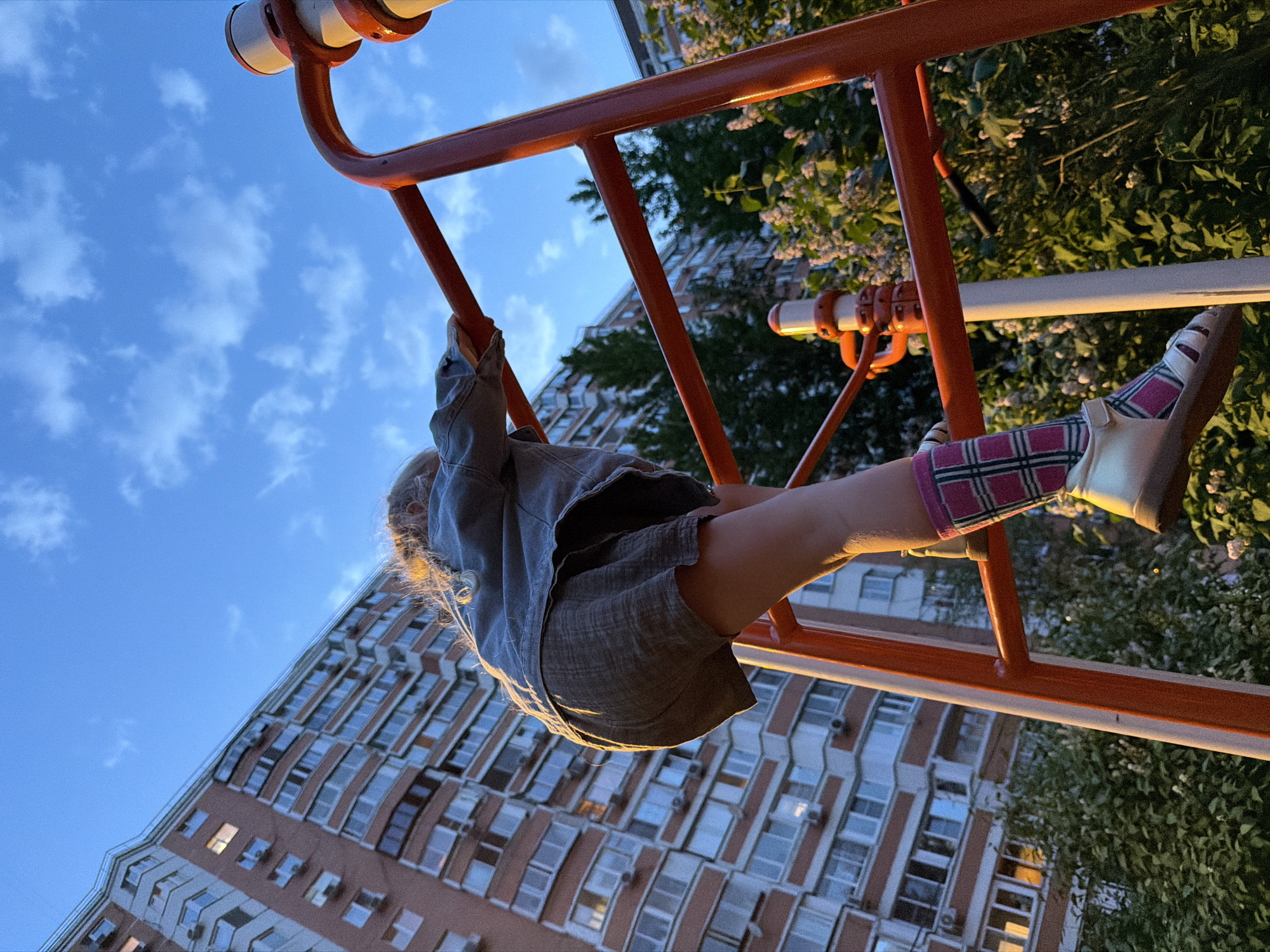 Child plays upside down on jungle gym in Moscow