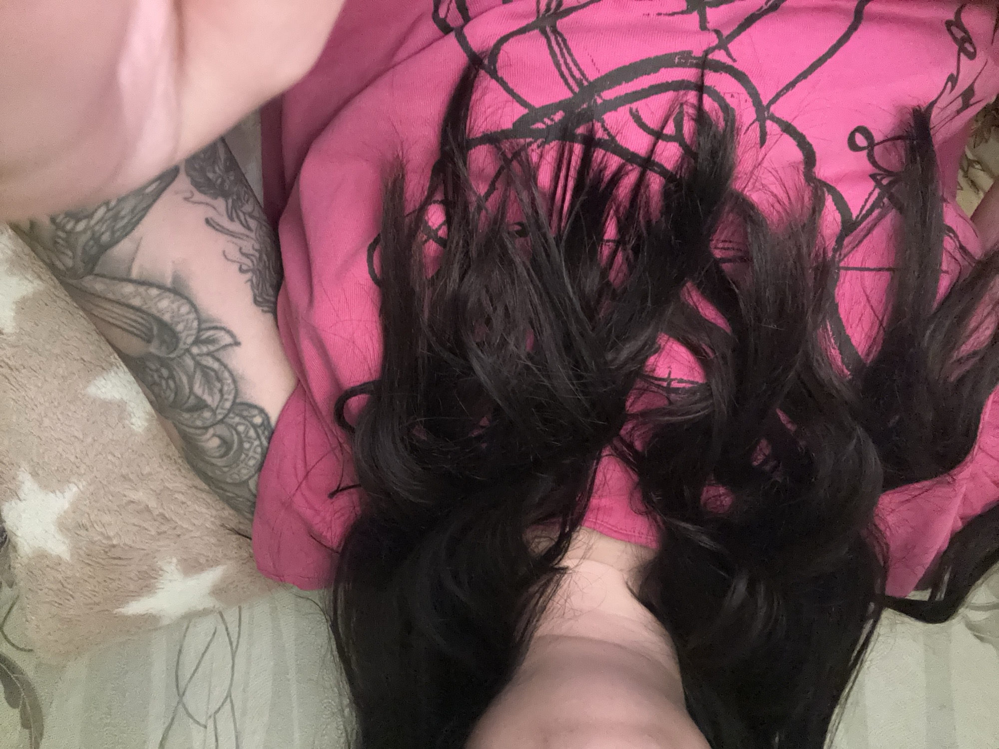 Person relaxing at home with tattoos, pink shirt, laptop
