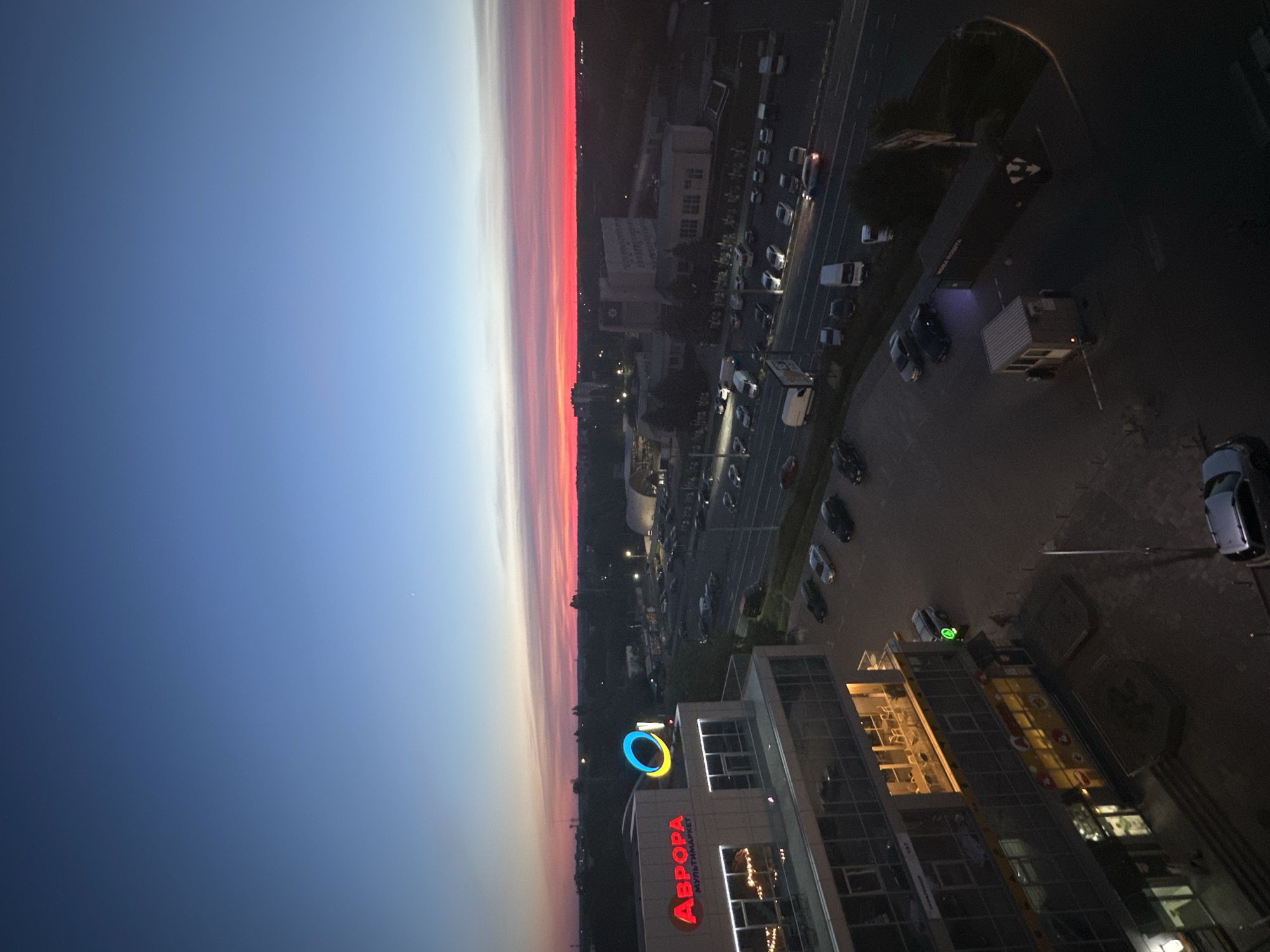 City skyline glows under a vivid red and pink sunset