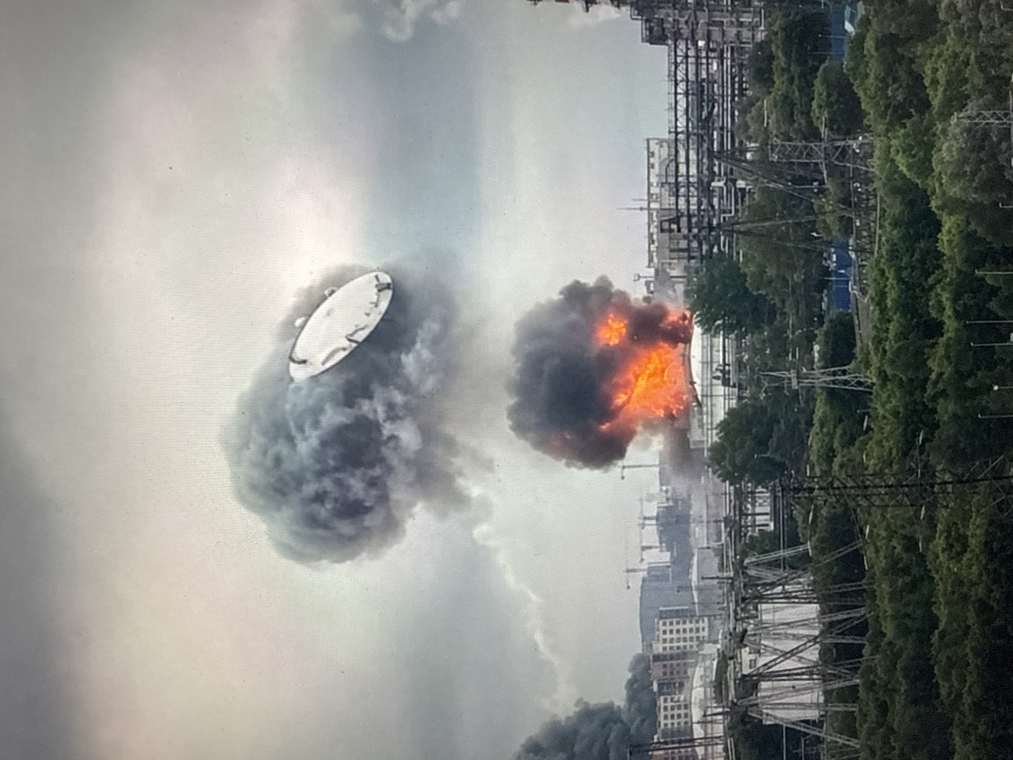 Industrial fire sends dark smoke across an urban skyline