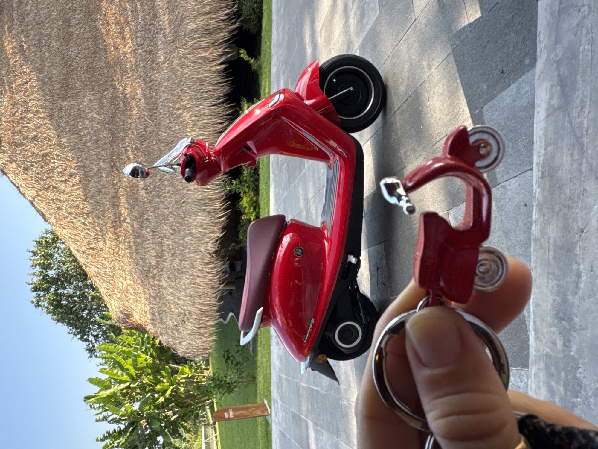Red electric scooter spotted near thatched building in Kediri