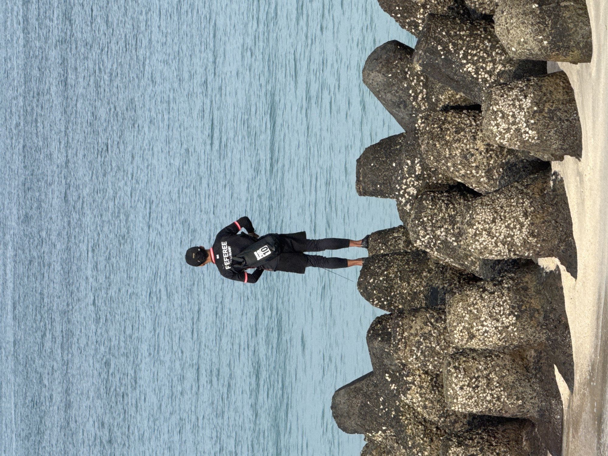 Man stands on breakwater facing ocean near Sanur Beach