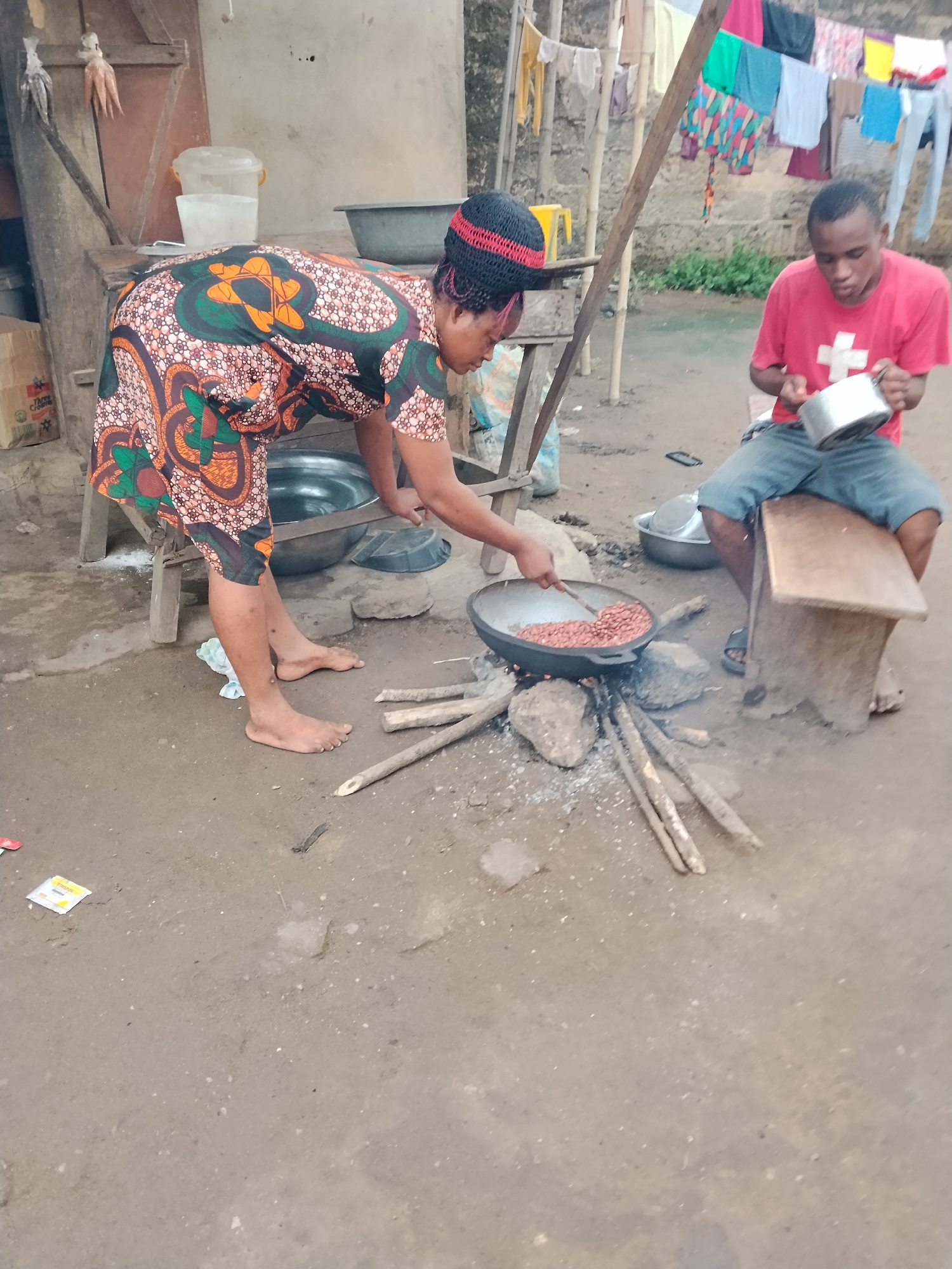 Woman cooks outdoors with large pan in urban setting