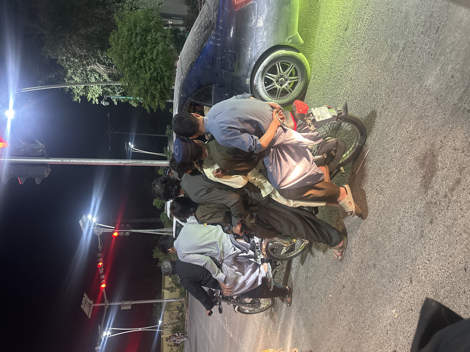Young men in traditional attire gather on nighttime street