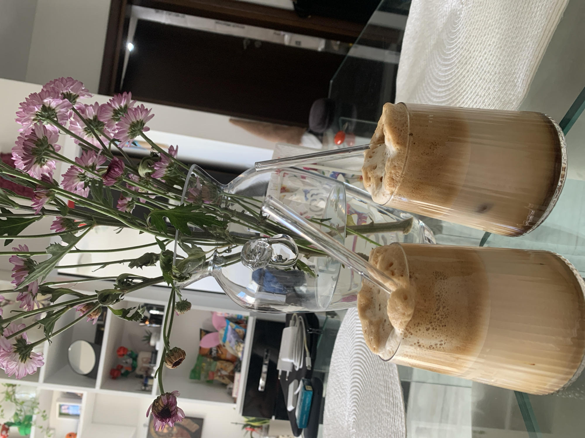 Morning still life: flowers and iced coffee on glass table