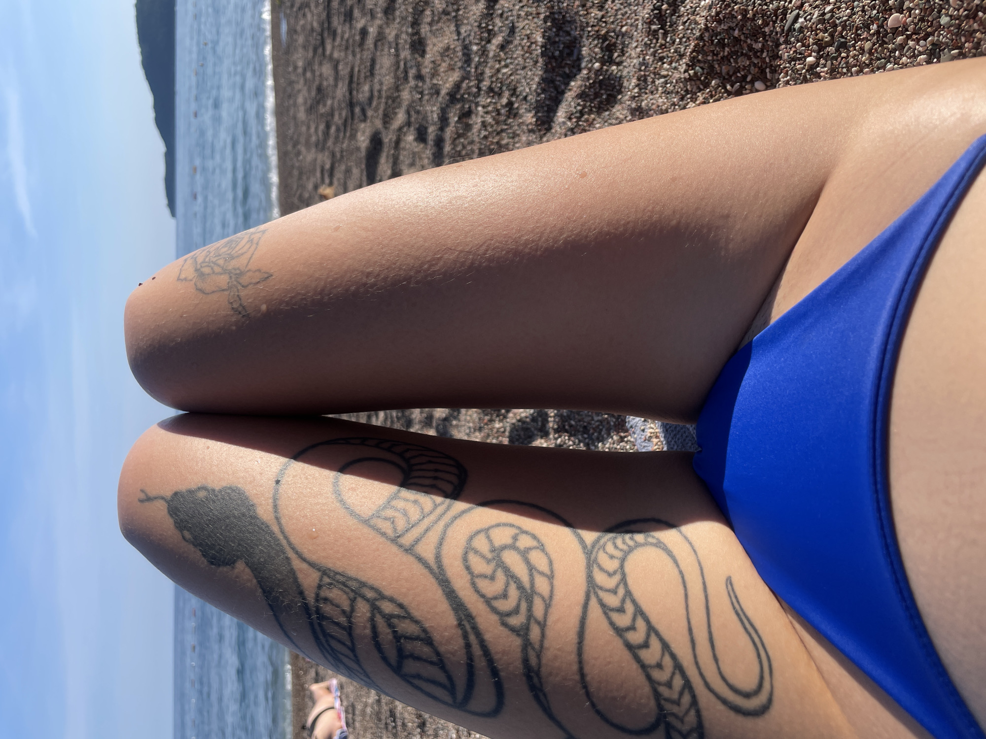 Tattooed woman sunbathing on Rafailovići beach, Montenegro