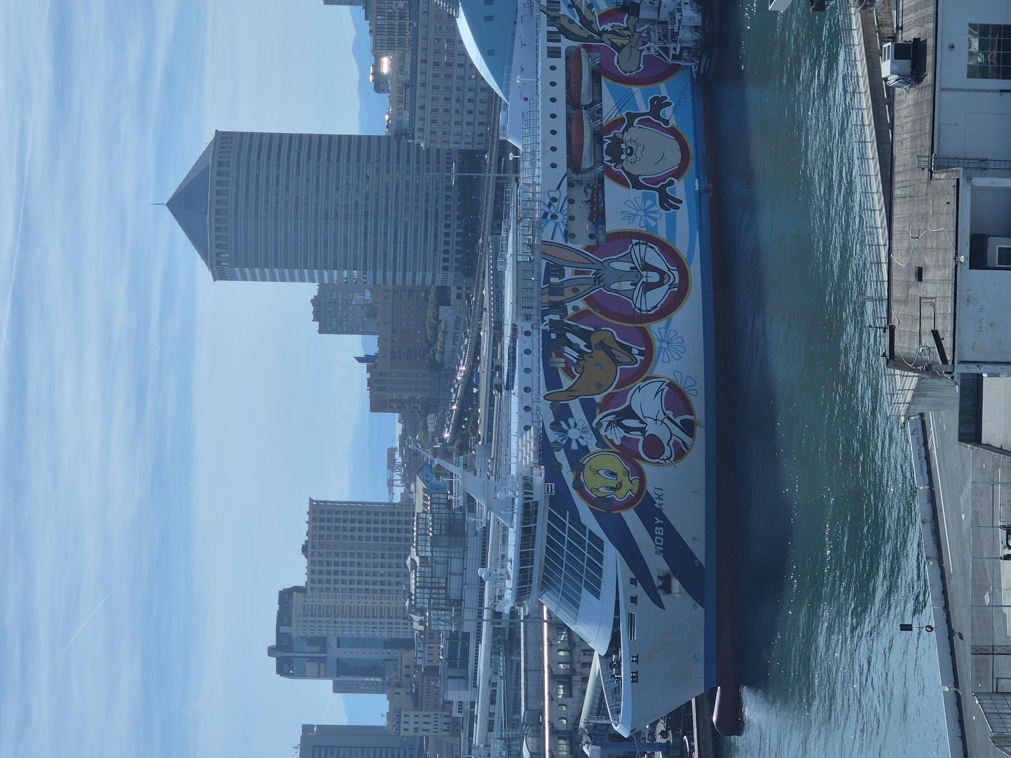 Cruise ship, tugboats spotted at Genoa Harbor during sunny afternoon