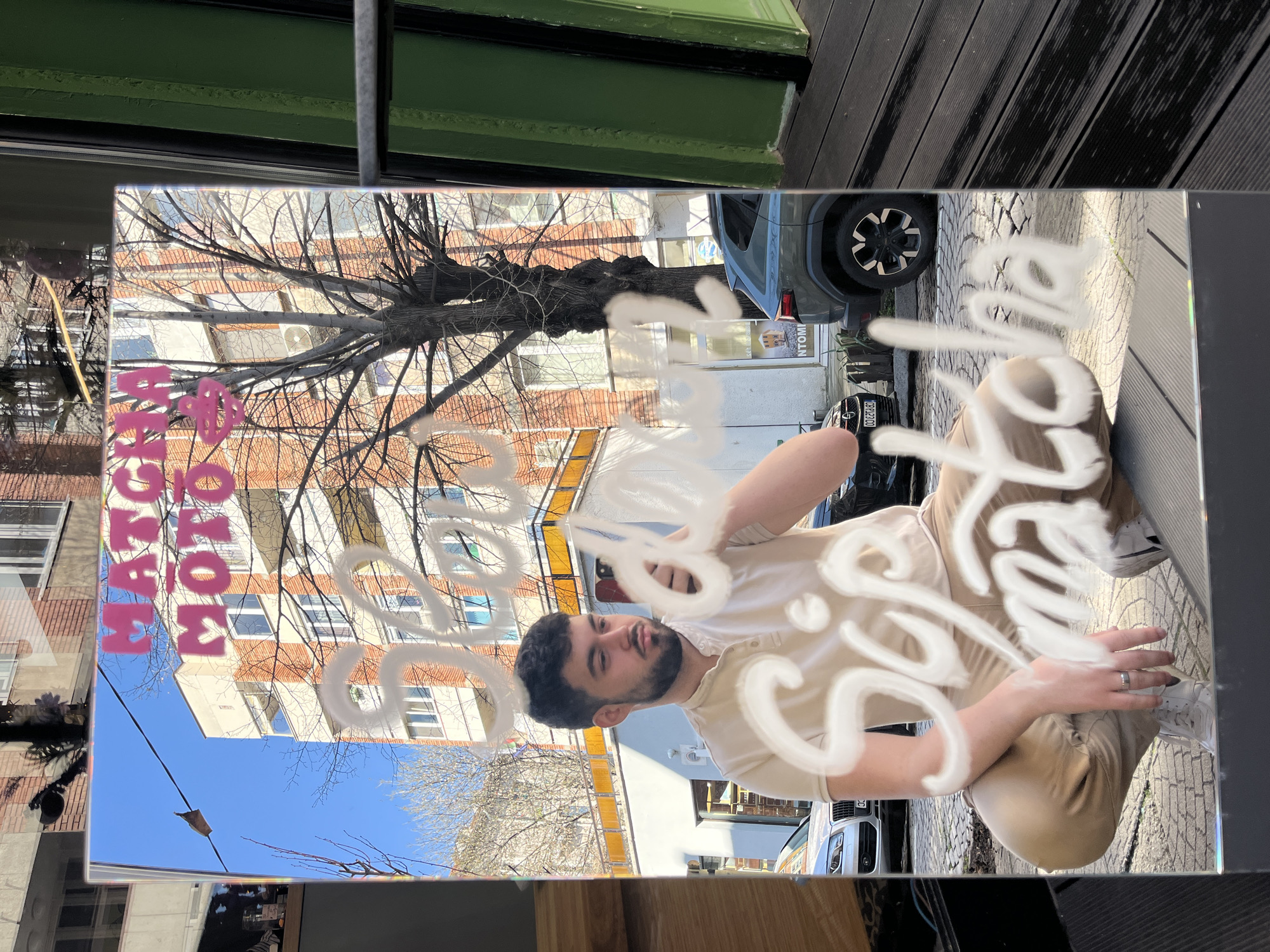 Man in tan clothing reflected in Sofia storefront glass