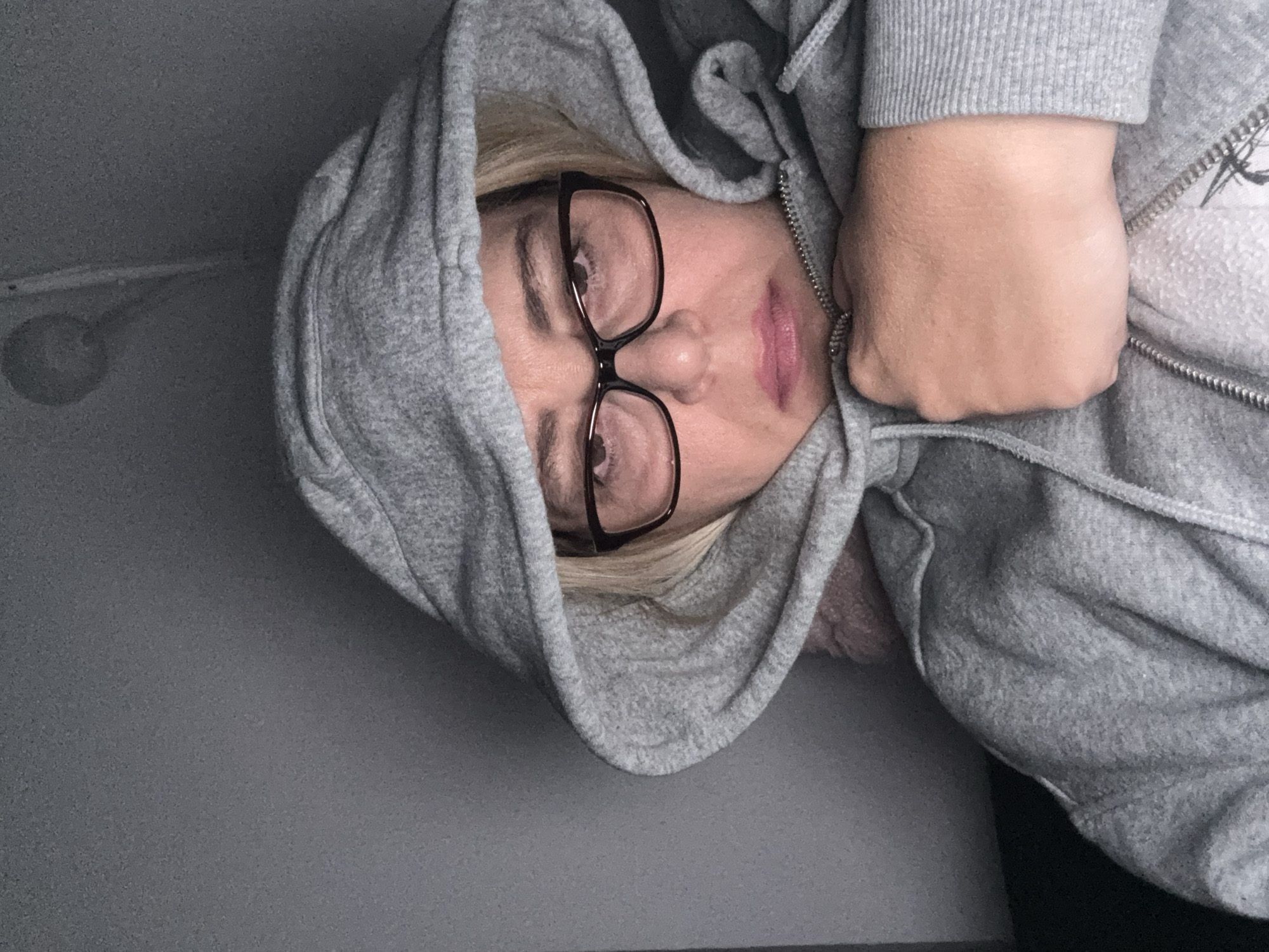 Hooded figure adjusts glasses in dimly lit room