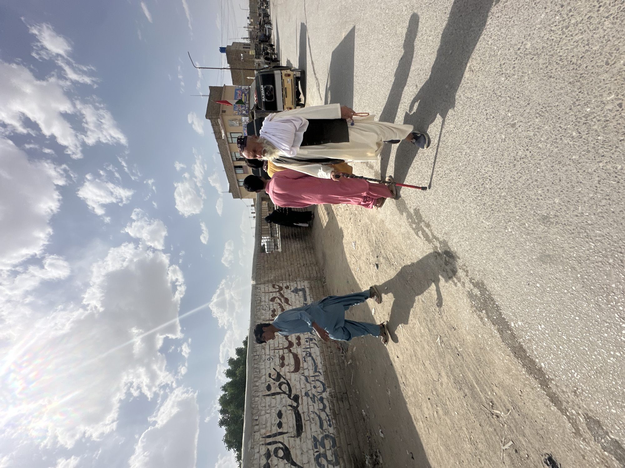 Elderly man walks with companions on Quetta road