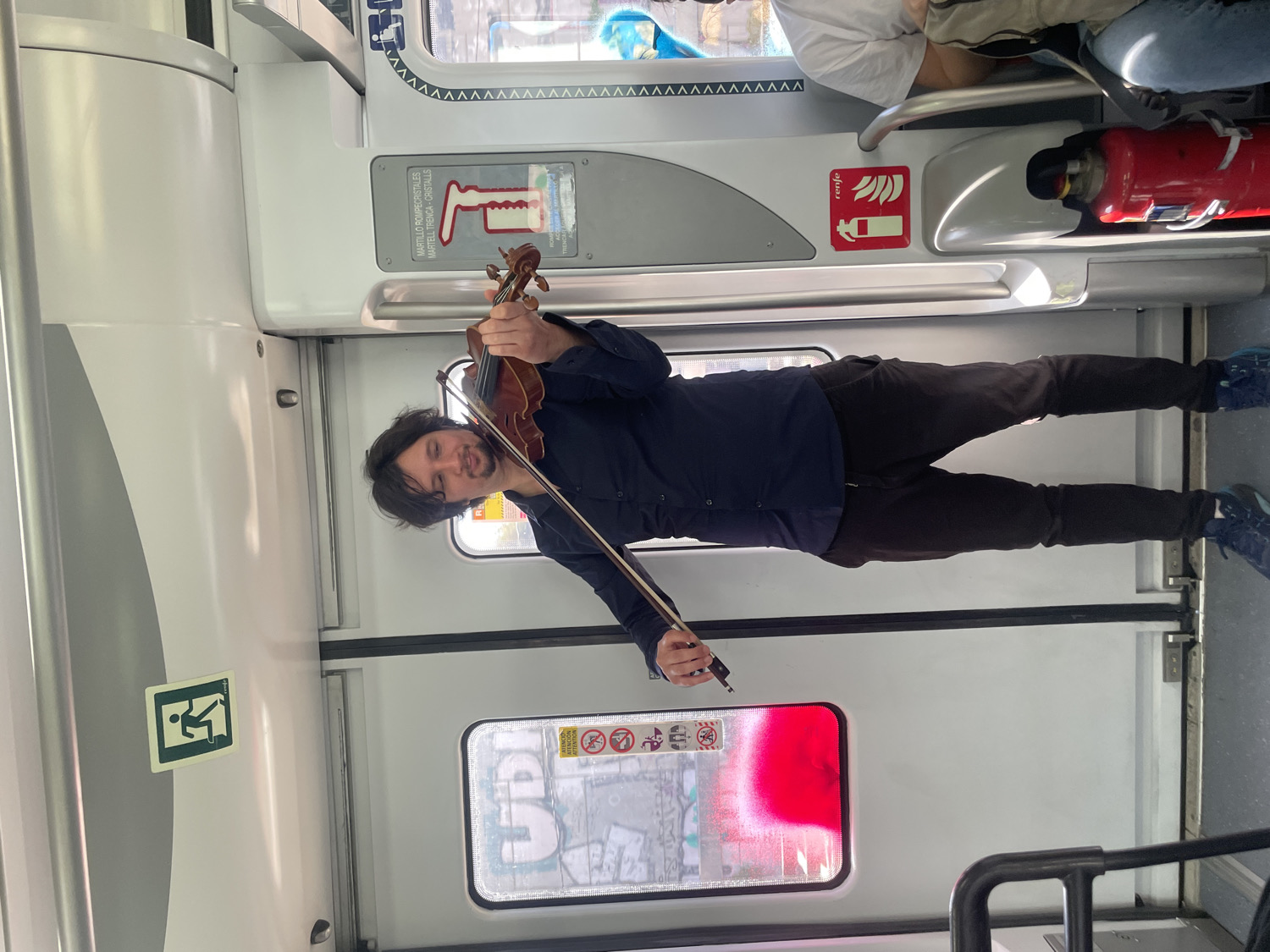 Street musician performs violin on metro train in Barcelona area