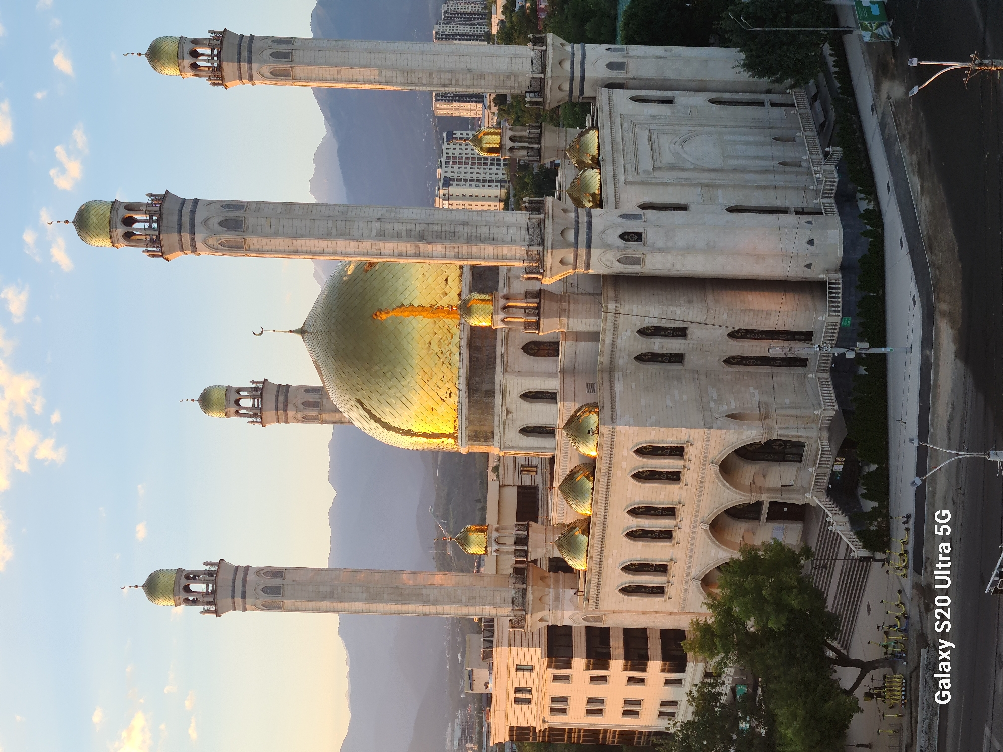 Almaty's Central Mosque at golden hour, mountains behind