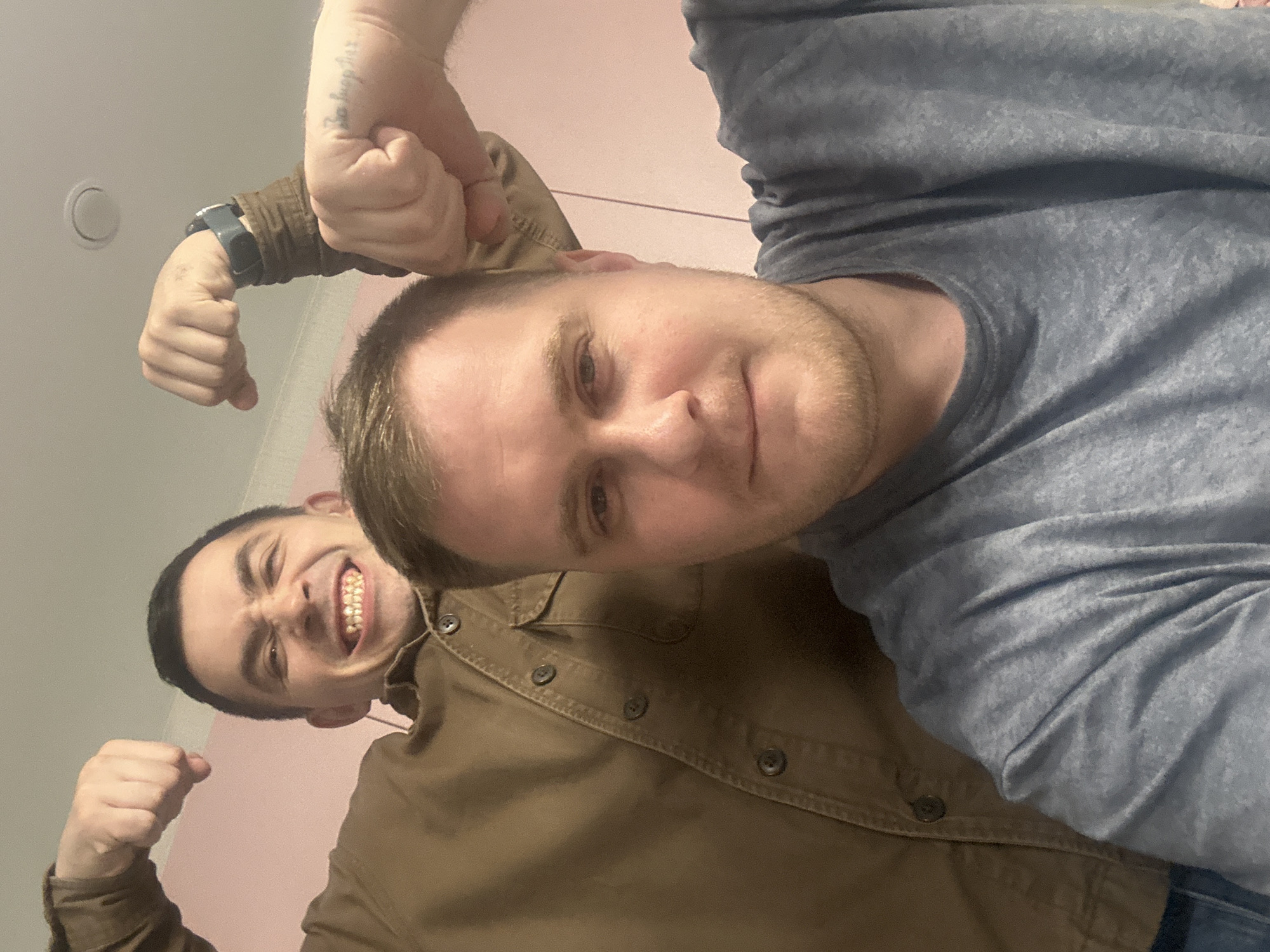 Two men pose for flexing selfie